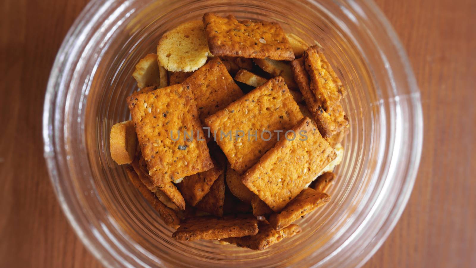 Wheat cracker in a glass jar on wooden table. by natali_brill