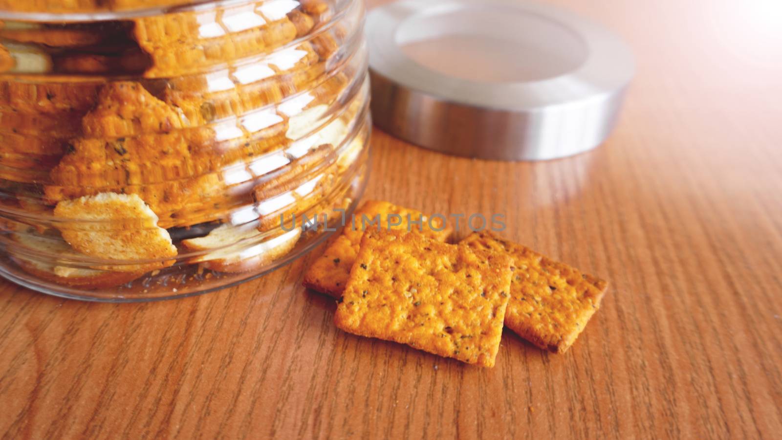 Wheat cracker in a glass jar on wooden table. by natali_brill