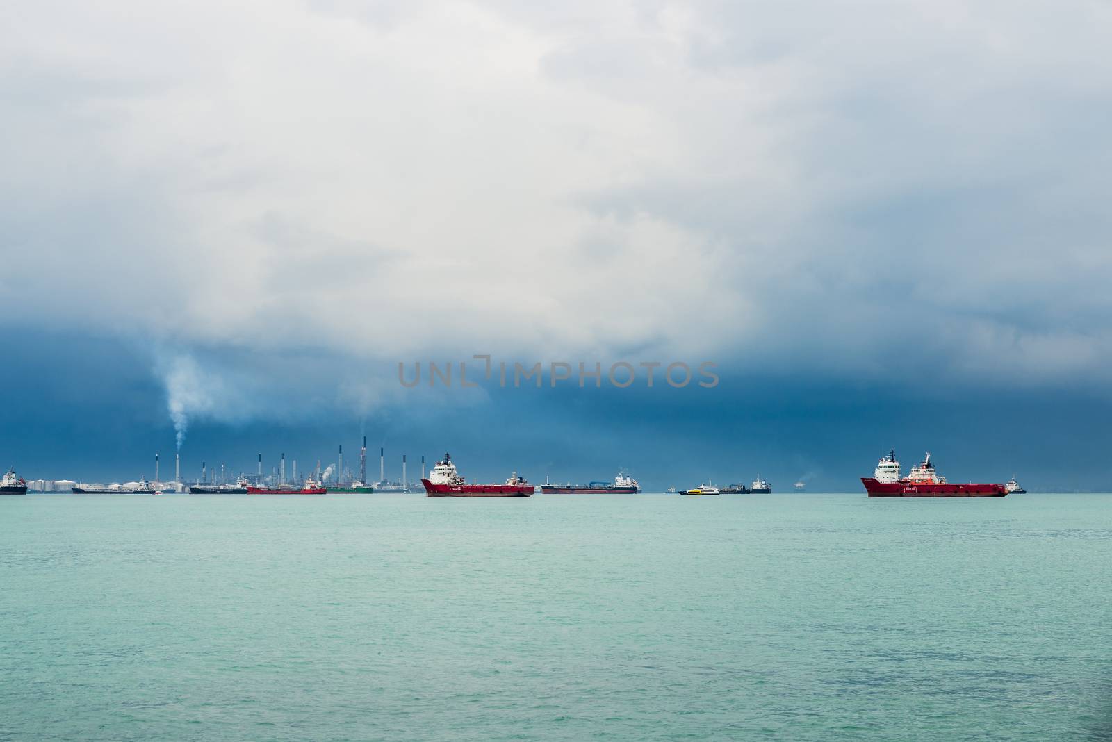 View of the Singapore Strait from Sentosa Island. Ships, industrial landscape and stormy weather.