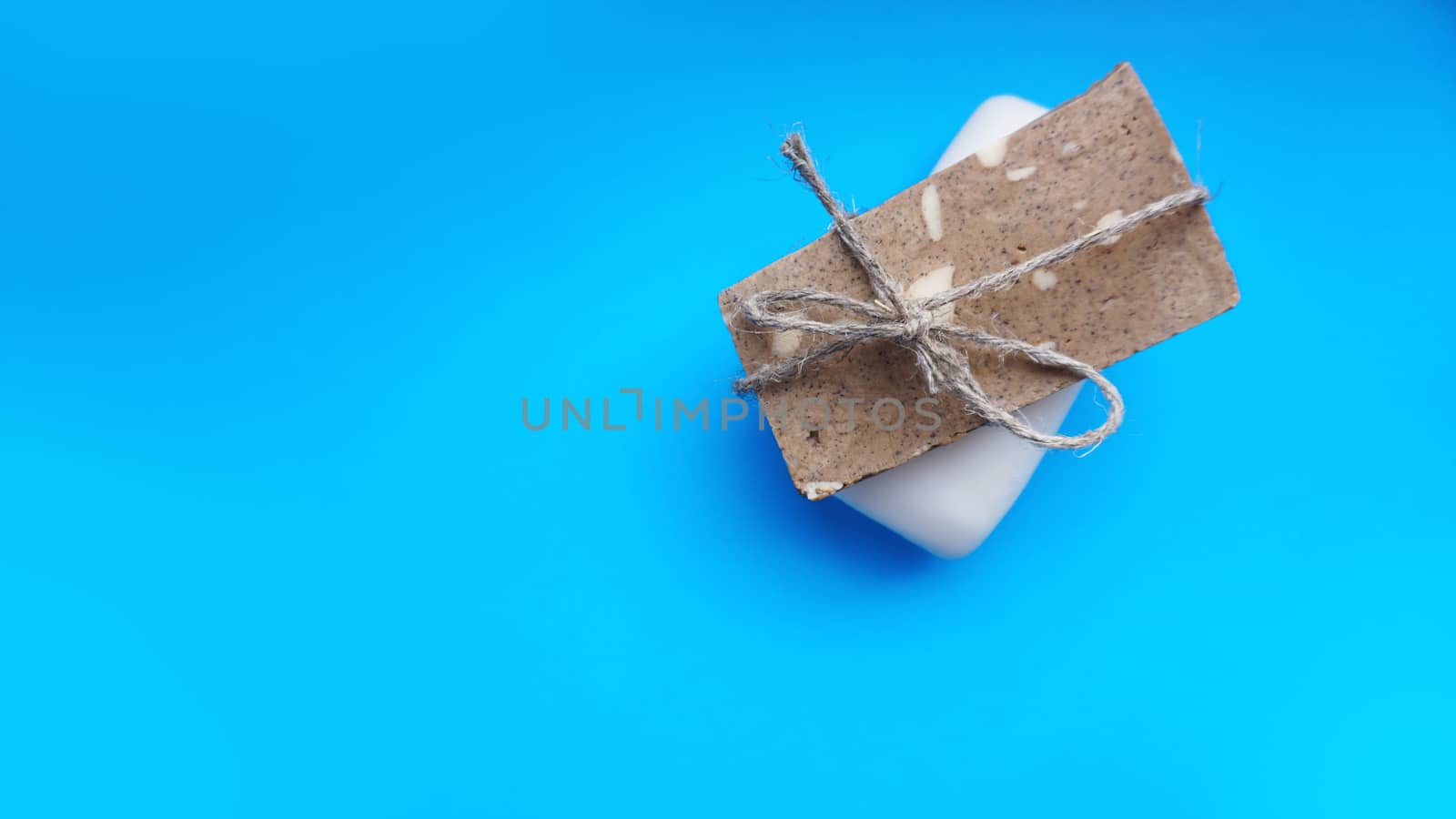 Gray and white Handmade soap wrapped with twine on a blue clean background