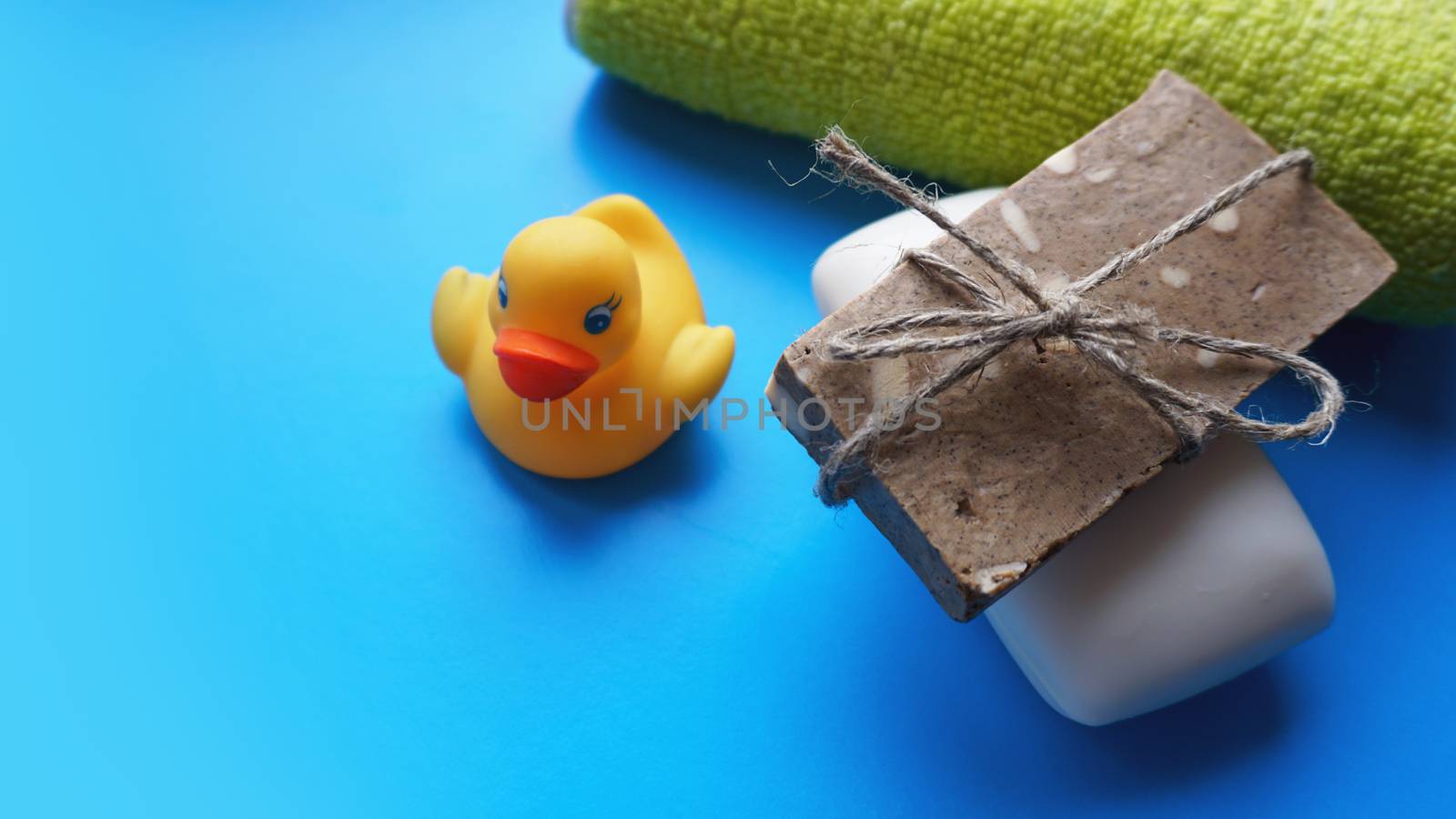 Terry towel, Gray and white Handmade soap and yellow toy duck on a blue background. Flat lay photo, top view