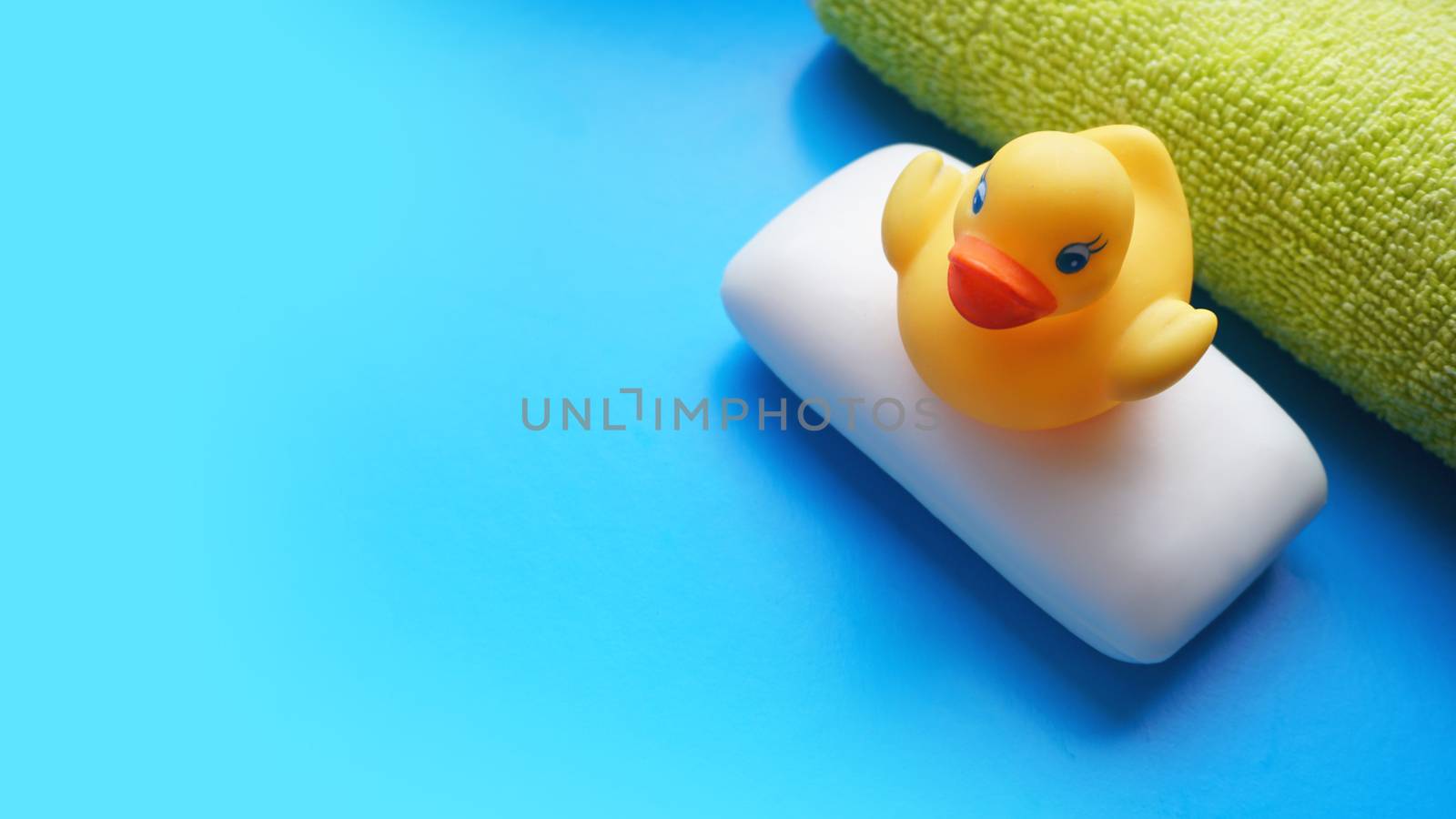 Terry towel, soap and yellow toy duck on a blue background. Flat lay photo, top view
