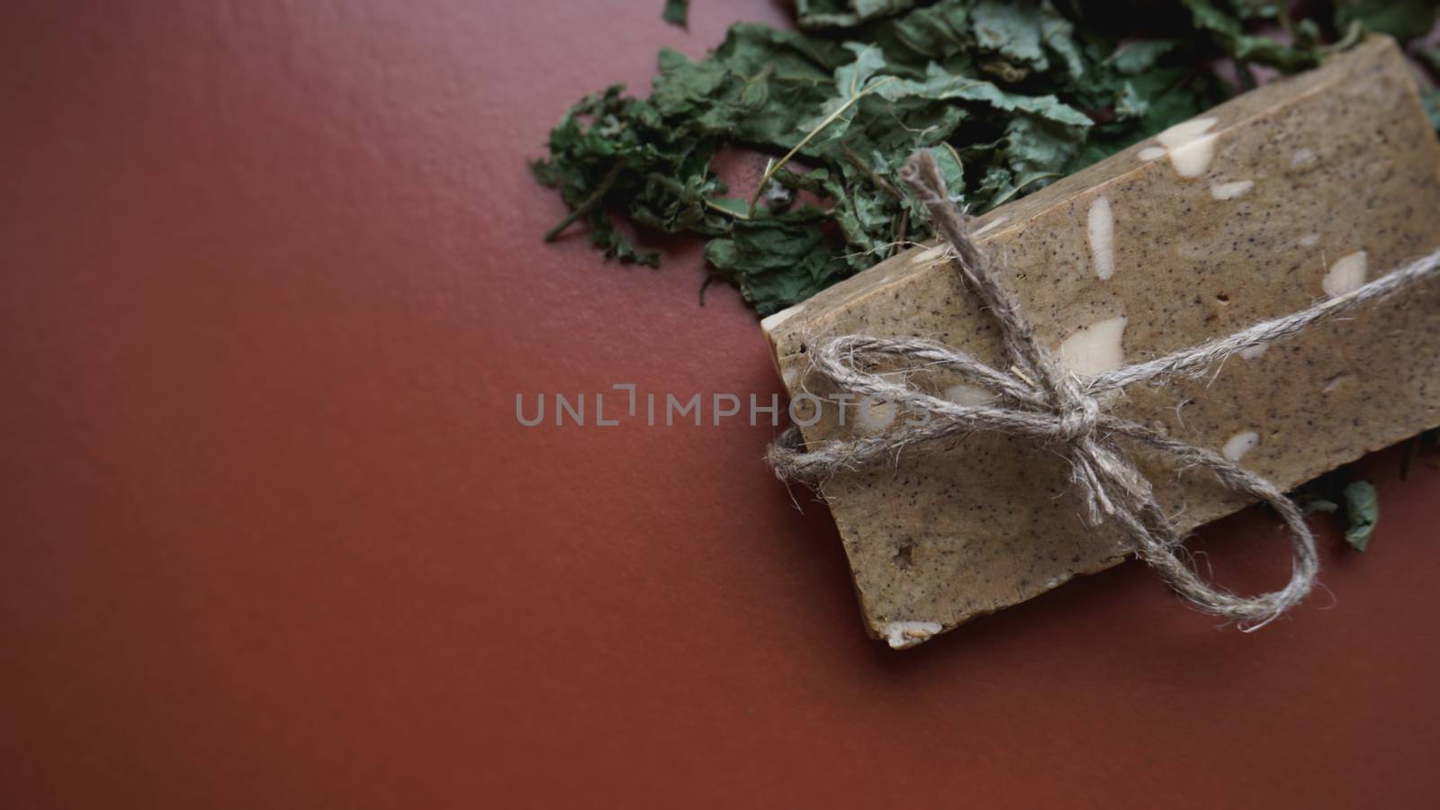 Organic handmade soap made of field herbs. Soap in a rope with dry grass on brown background
