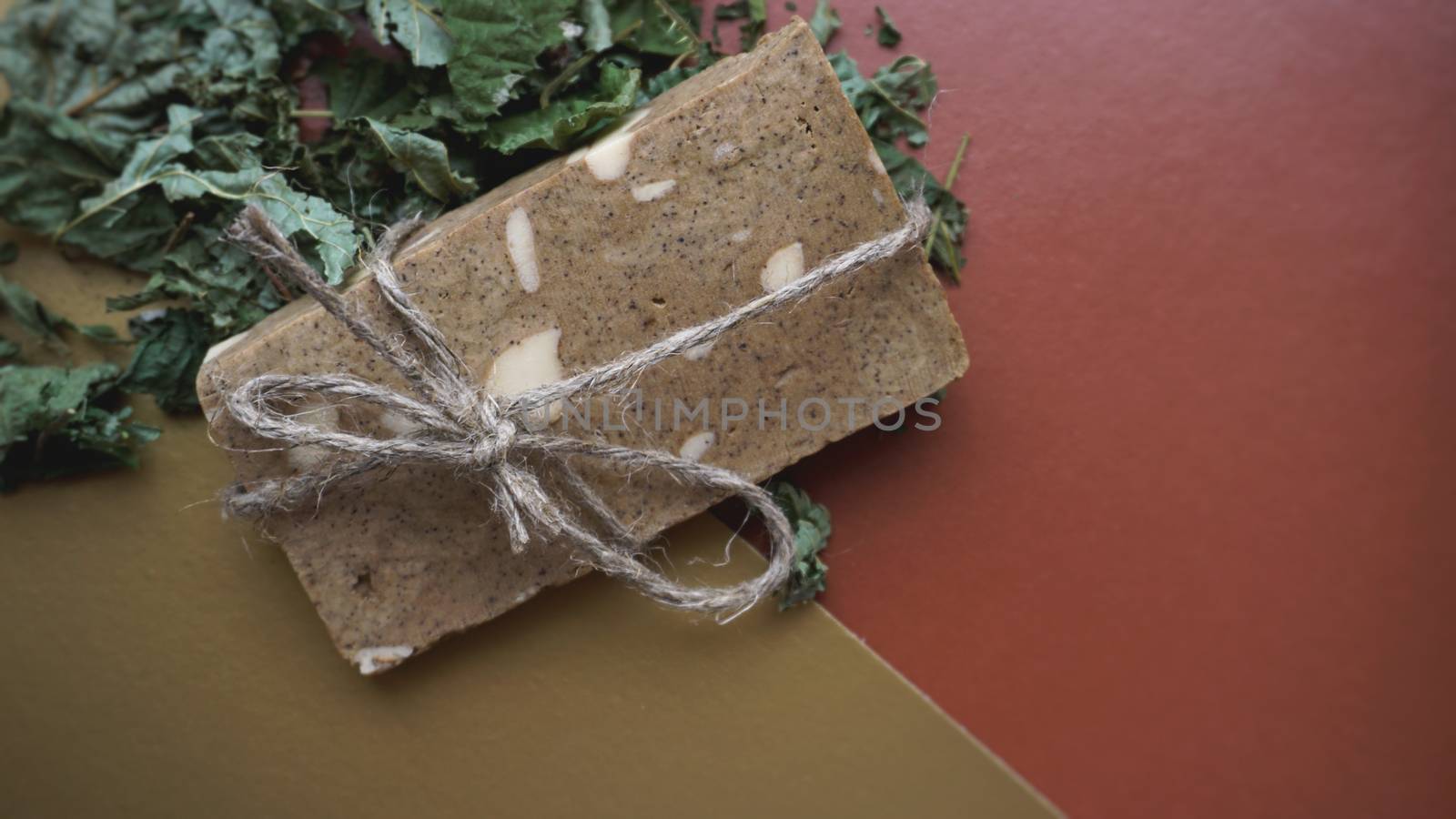 Organic handmade soap made of field herbs. Soap in a rope with dry grass on a golden and brown background