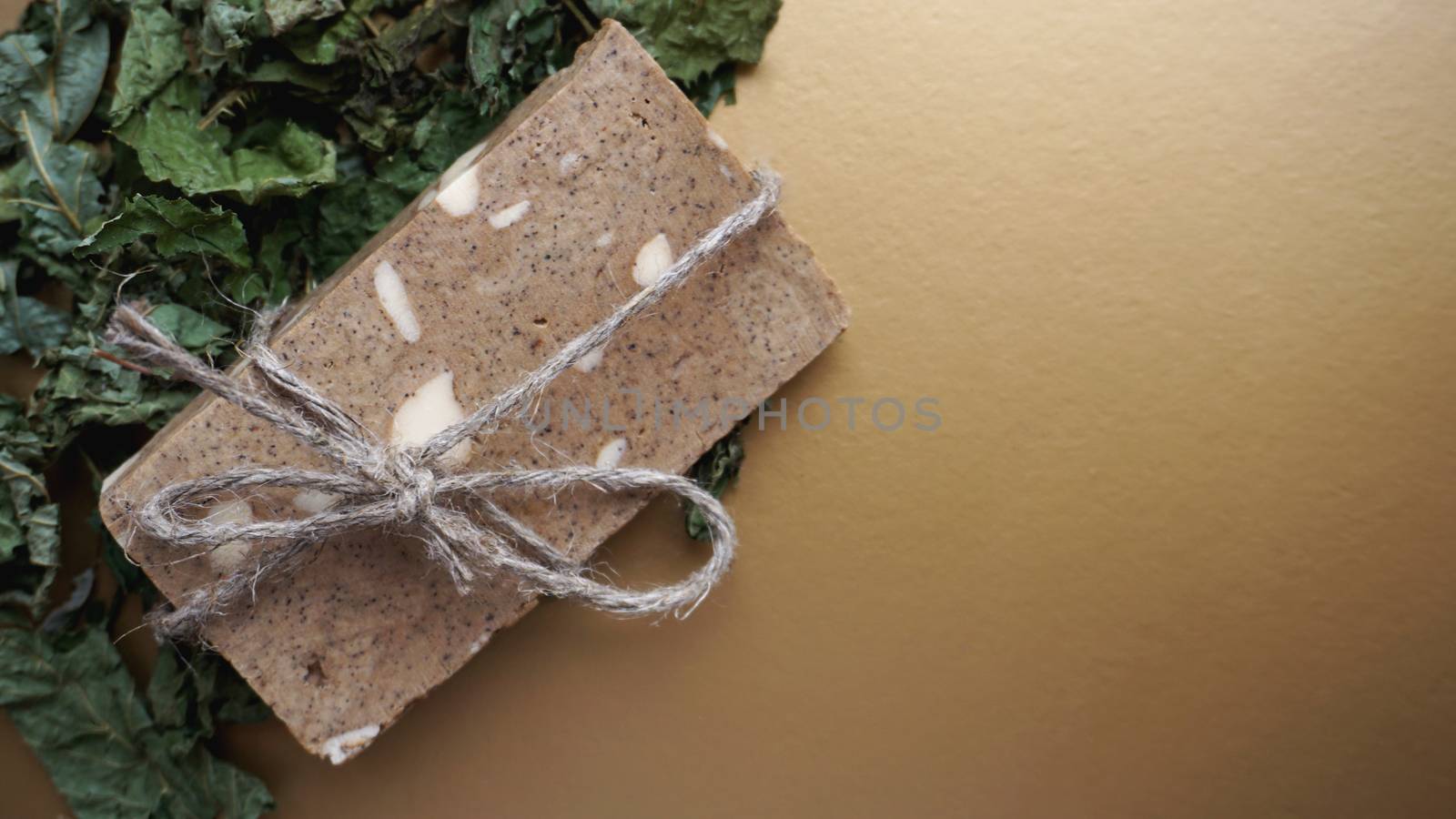 Organic handmade soap made of field herbs. Soap in a rope with dry grass on a golden background