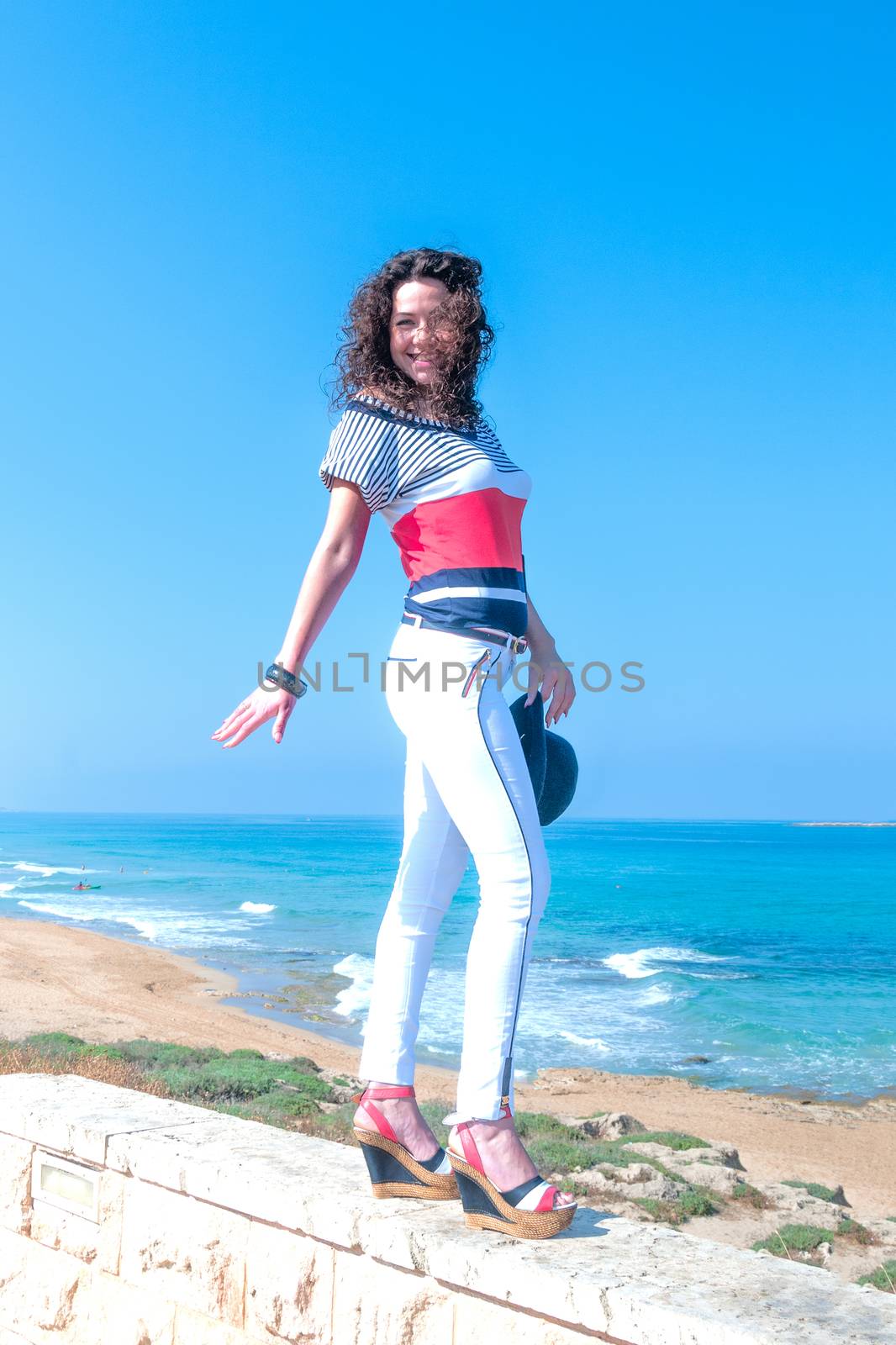 Cheerful girl in white jeans is balancing on the parapet by ben44