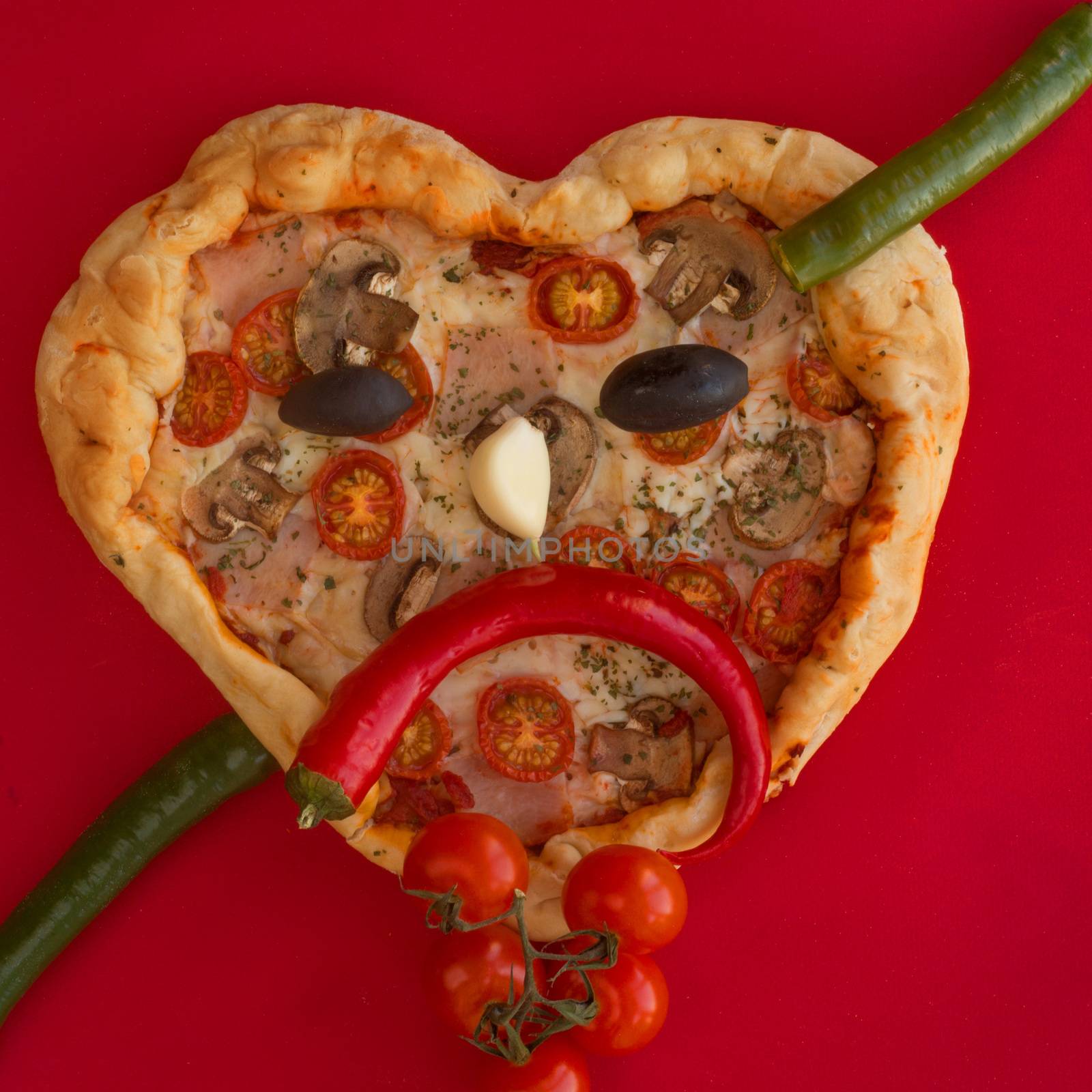 Pizza heart shaped with ham tomatoes and mushrooms on red background . Sad face heartbreak , Concept of romantic love for Valentines Day . Love food