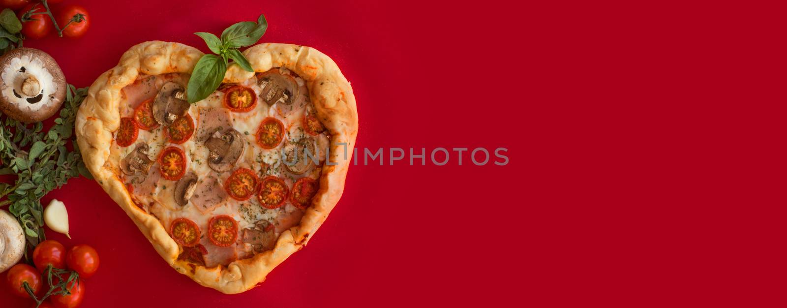 Pizza heart shaped with ham tomatoes and mushrooms on red background . Concept of romantic love for Valentines Day . Love food