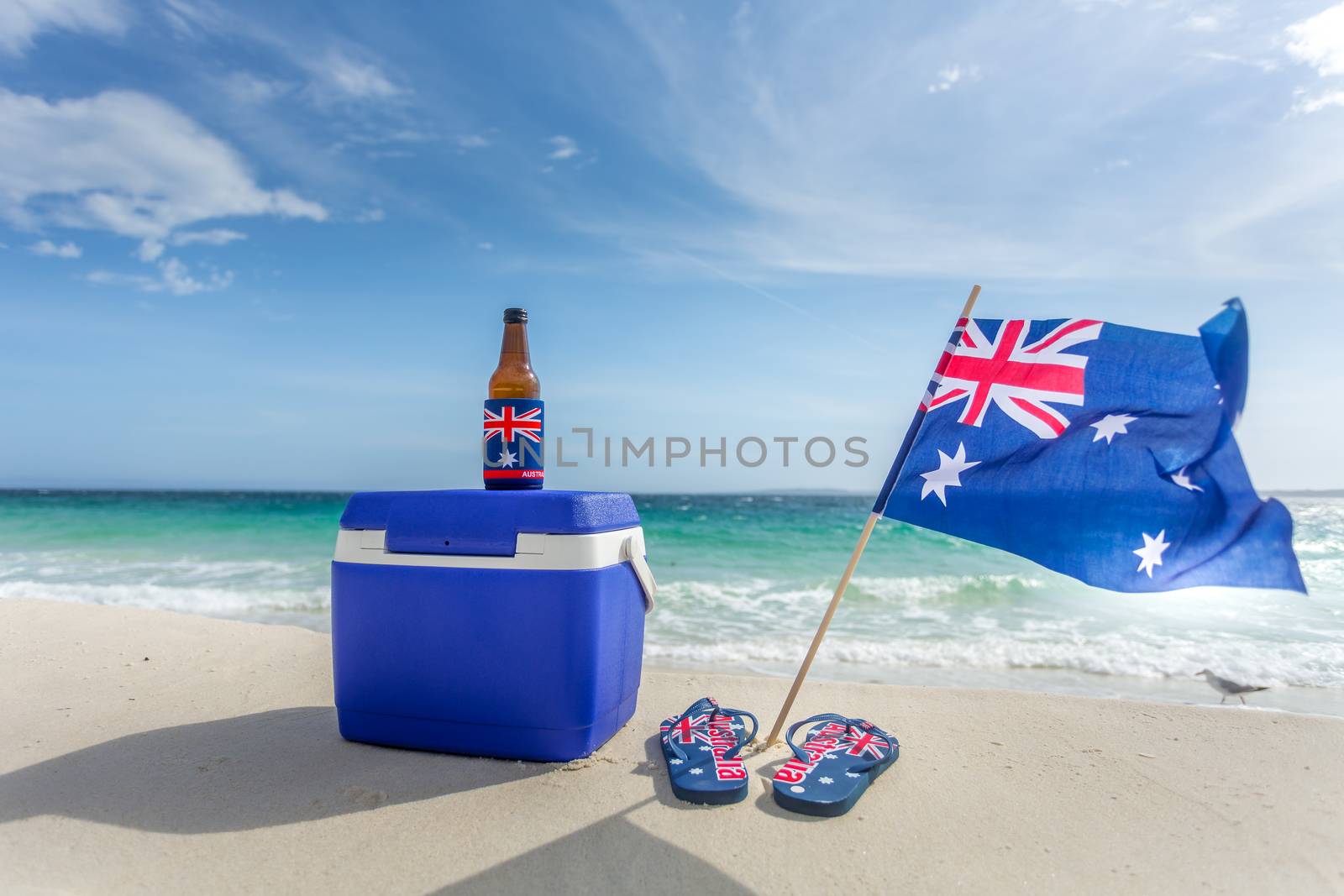 Quinessentially Australian summer.  Esky, beer bottle in a cooler, thongs and Australian flag on a beautiful beach on summer day