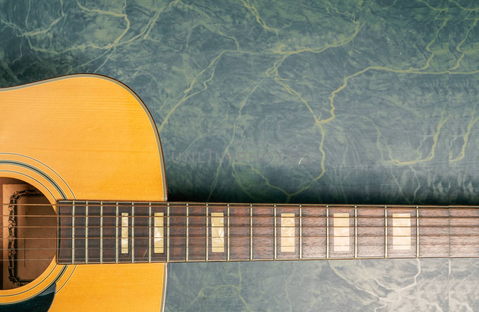 acoustic guitar on green marble close up by Robertobinetti70