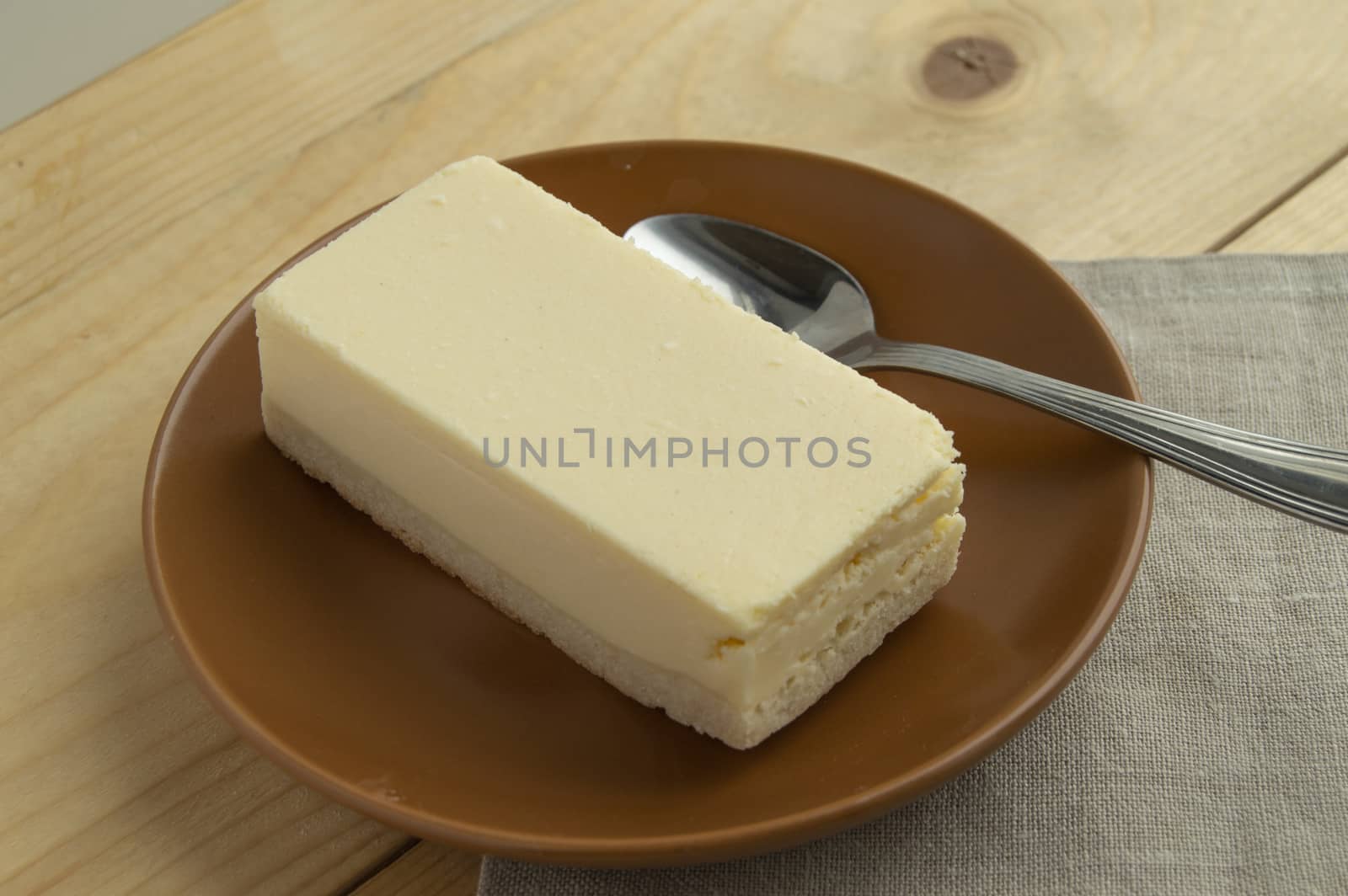 A piece of classic vanilla new York cheesecake on a light wooden background and linen napkin by claire_lucia