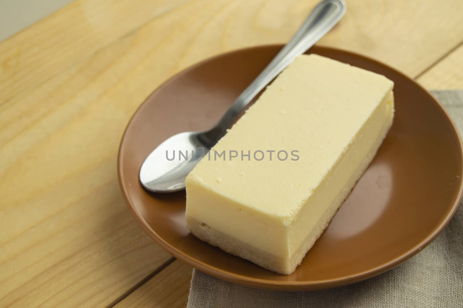 A piece of classic vanilla new York cheesecake on a light wooden background and linen napkin by claire_lucia