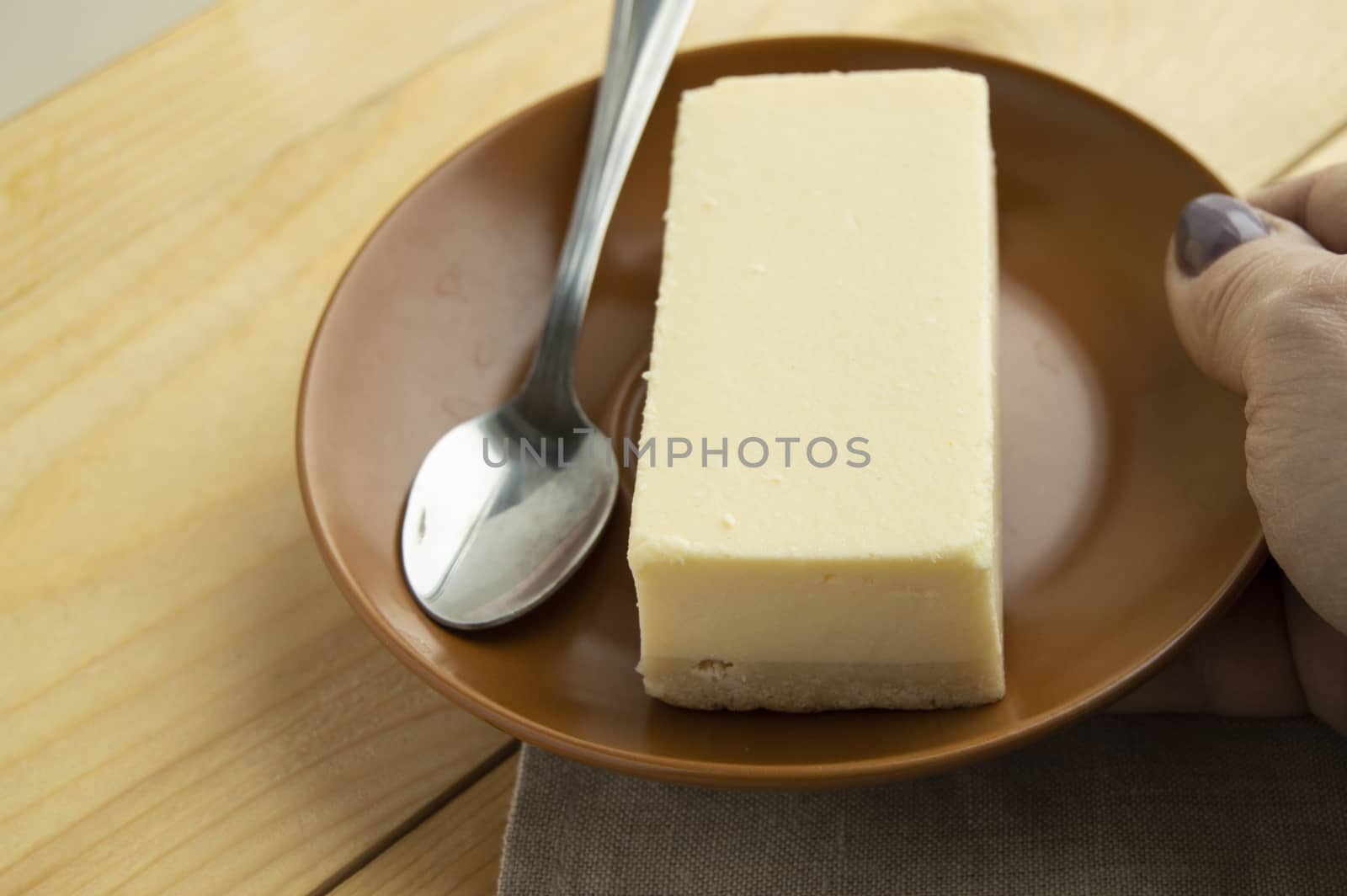 A piece of classic new York vanilla cheesecake on a light wooden background and linen napkin, close-up