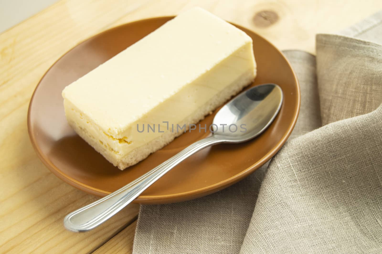 A piece of classic vanilla new York cheesecake on a light wooden background and linen napkin by claire_lucia