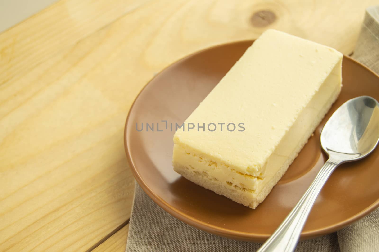A piece of classic vanilla new York cheesecake on a light wooden background and linen napkin by claire_lucia