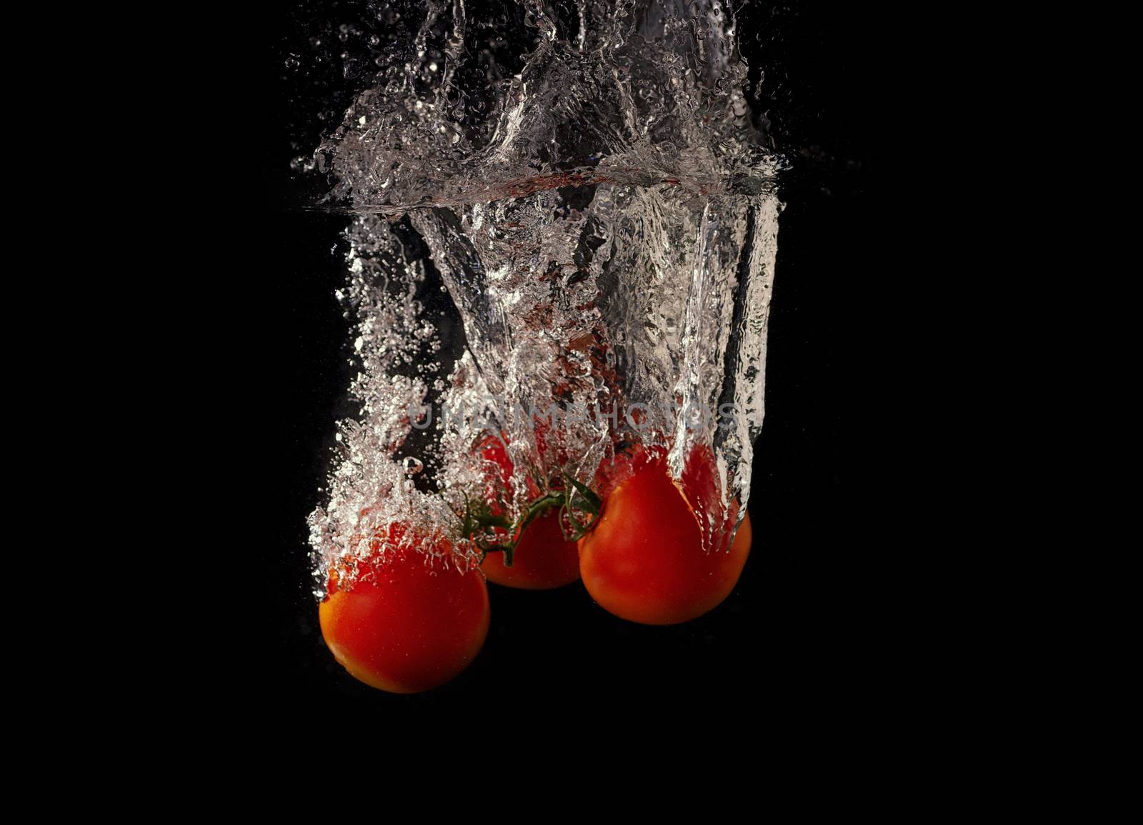 Vegetables tomatoin water splash on black background