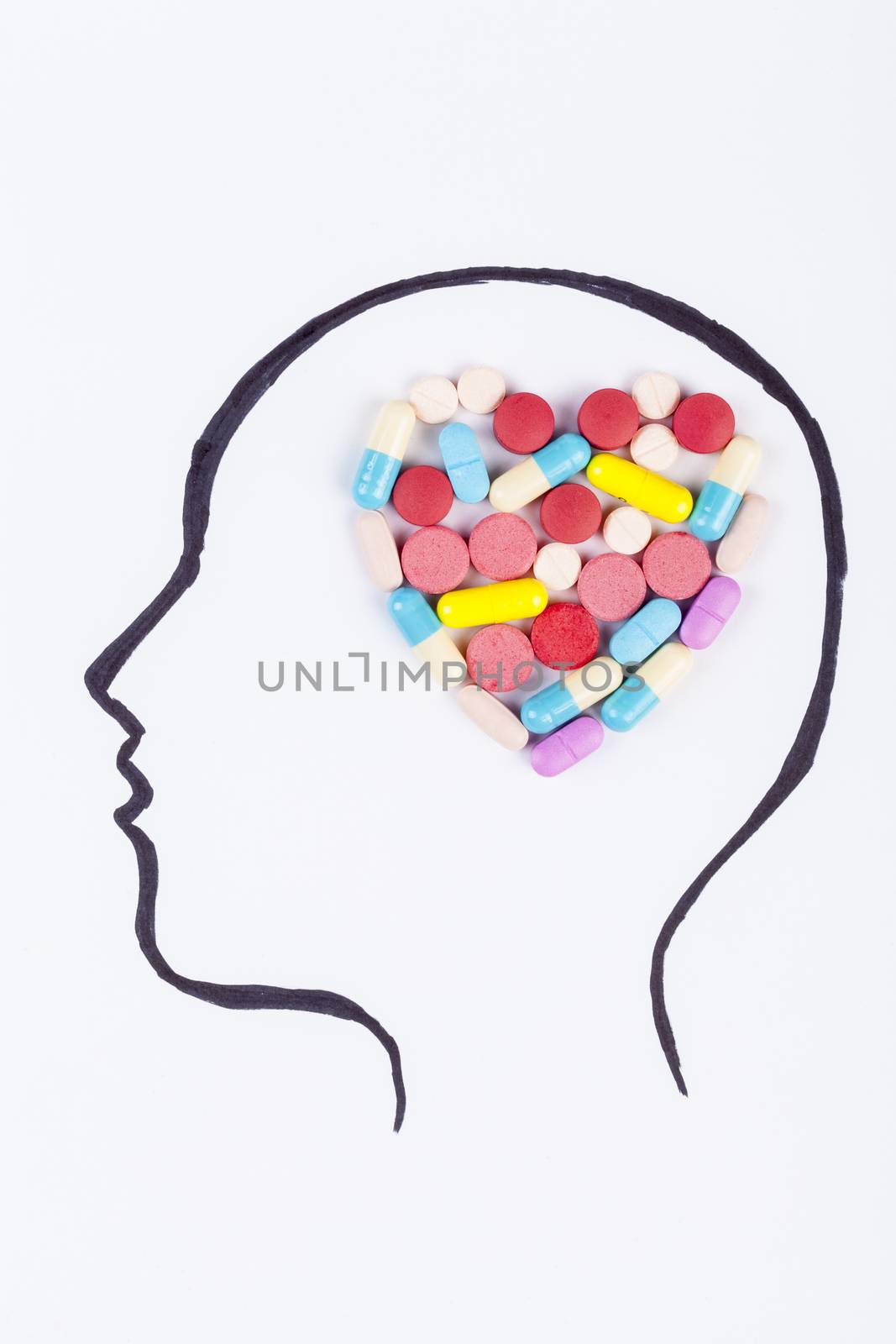 Human head hand drawing with heart shape colored pills in the brain