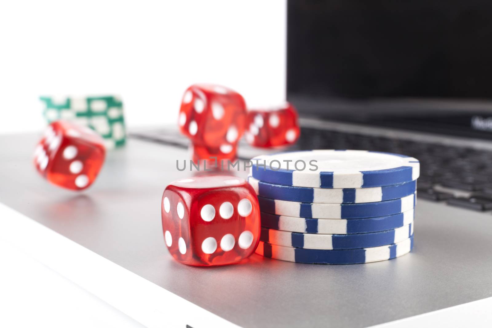 Red casino dices with chips on silver laptop isolated on white background