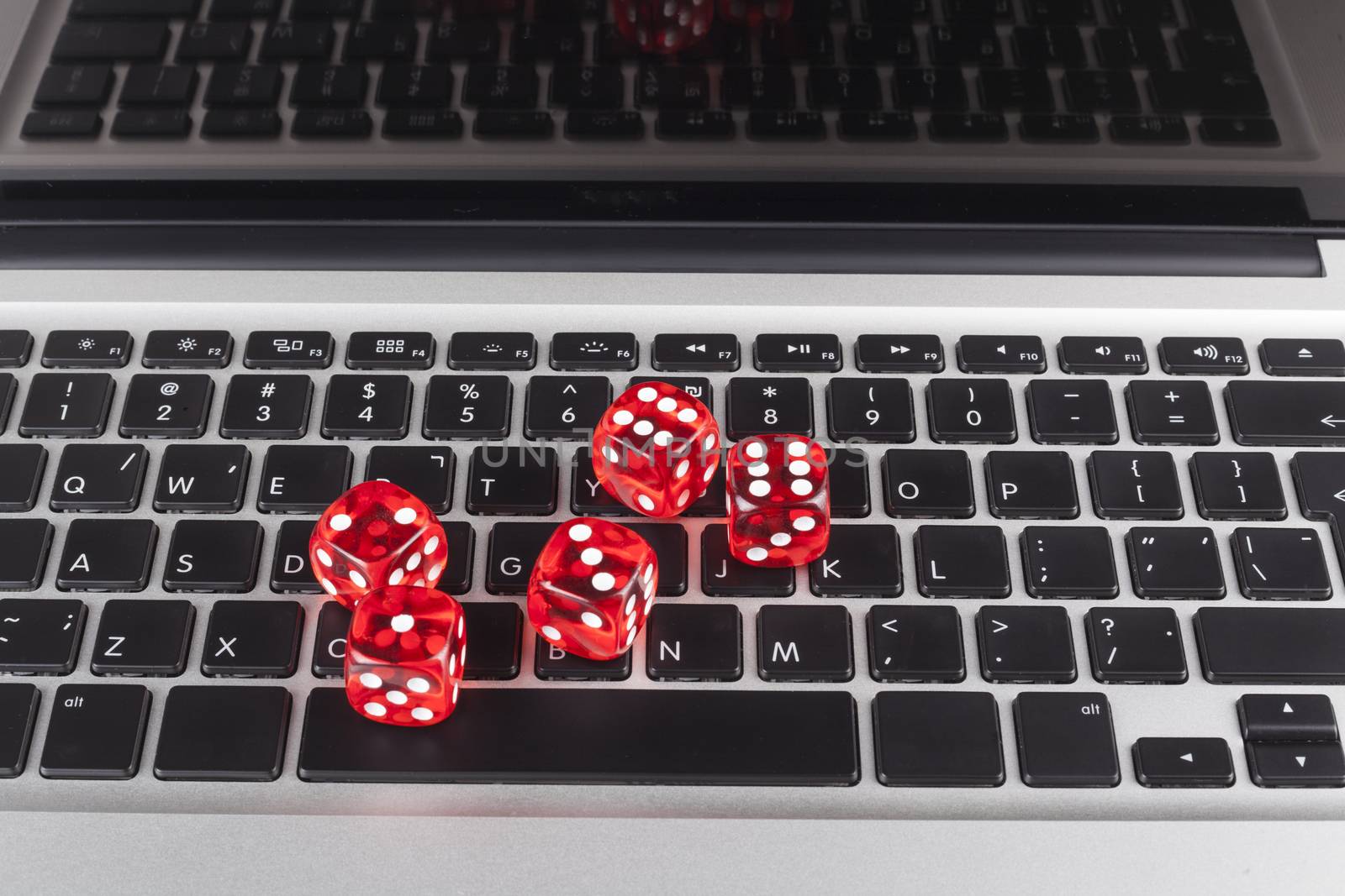 Red casino dices with chips on silver laptop with black Keyboard