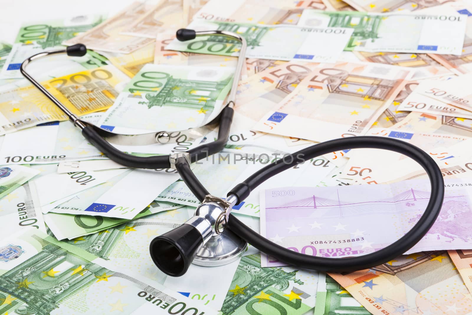 Black stethoscope  on pile of euro banknotes closeup isolated on white background