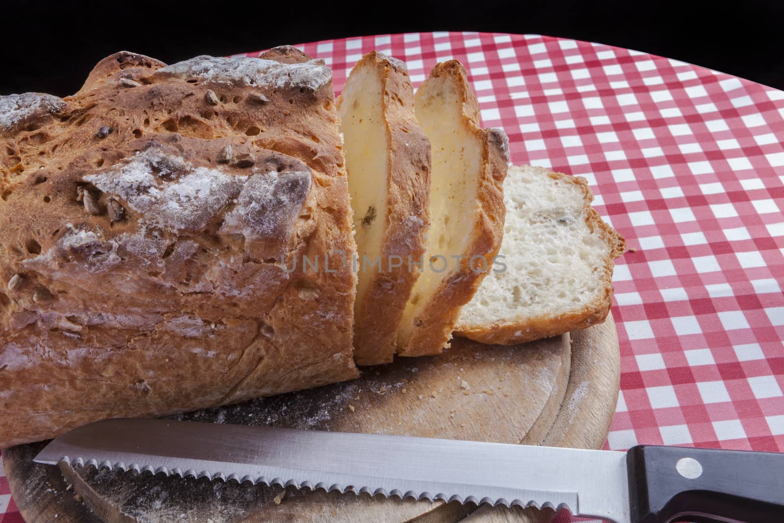 Sliced bread on round wood plate and red table with black on the background