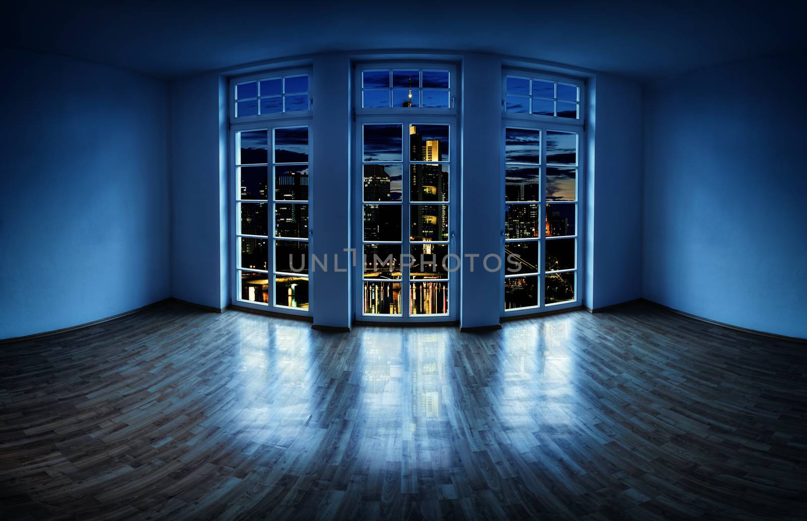 View from an empty apartment through a large window to a lit city at night