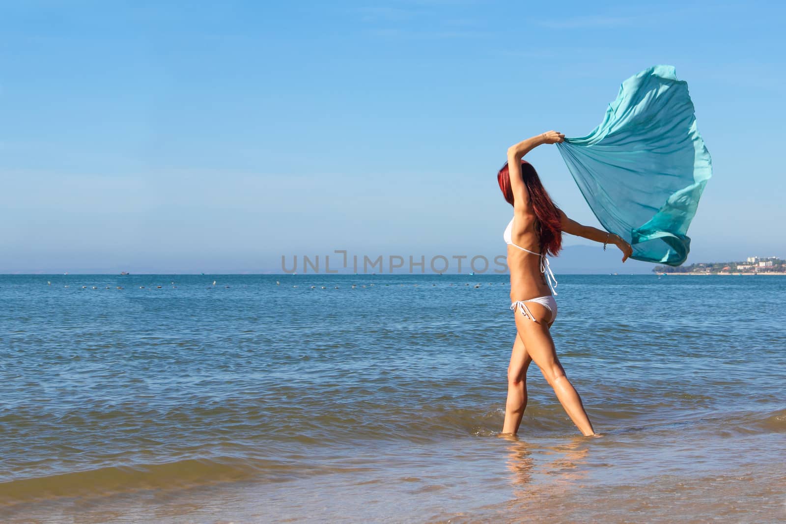 Young slim Woman in bikini walks on tropical beach in Vietnam