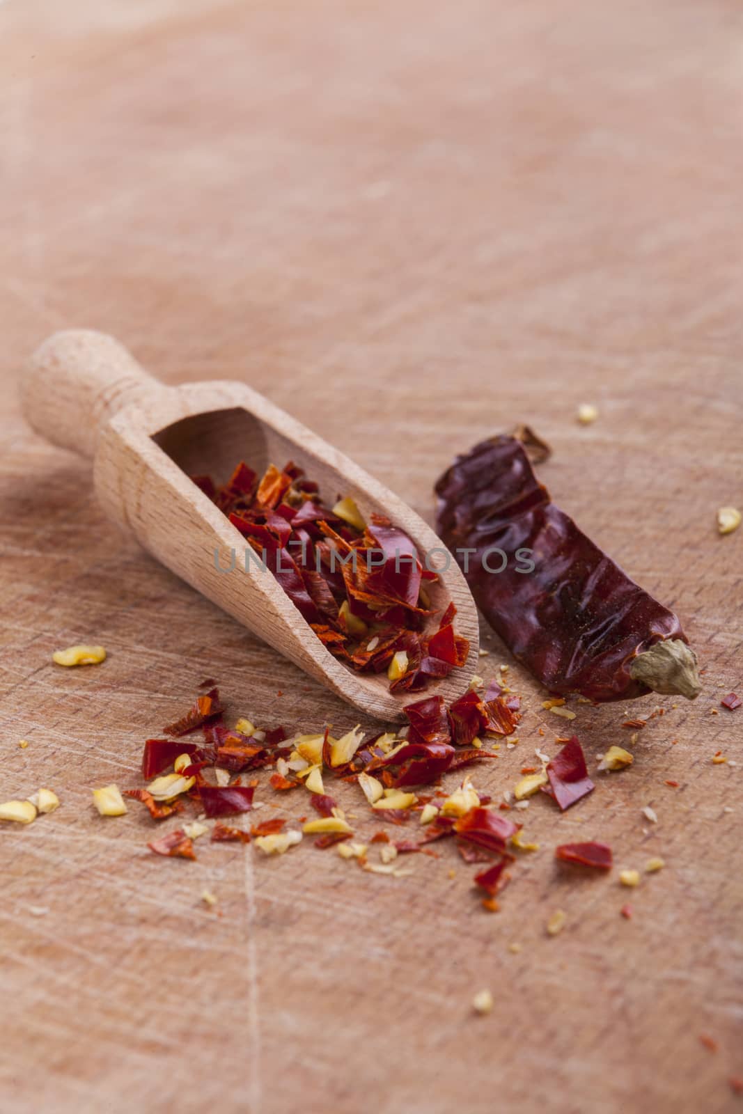 Dry red hot chilli peppers with wooden spoon on brown wood background