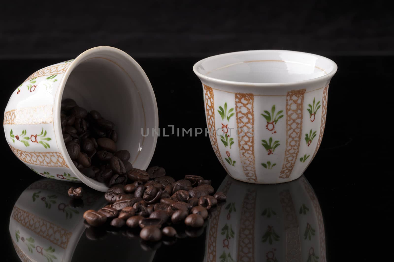 Hand painted traditional arabic coffee cups on black background and coffee  beans with reflection