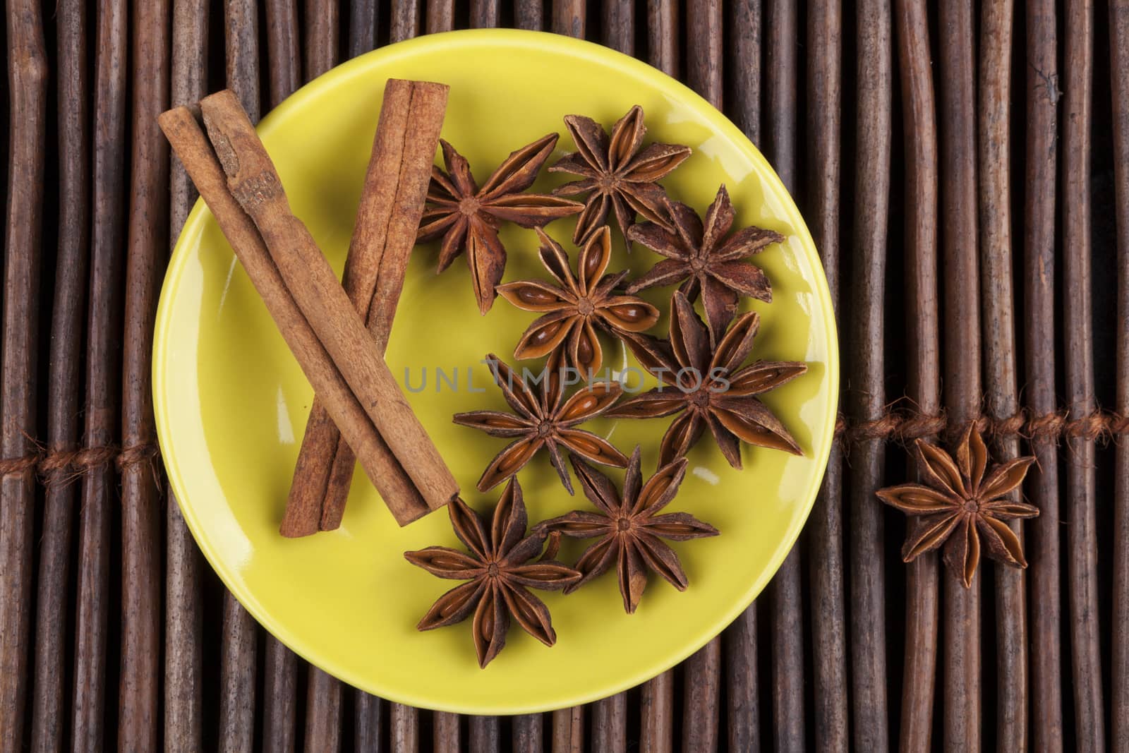Cinnamon sticks with star shape anis on green plate and wood background