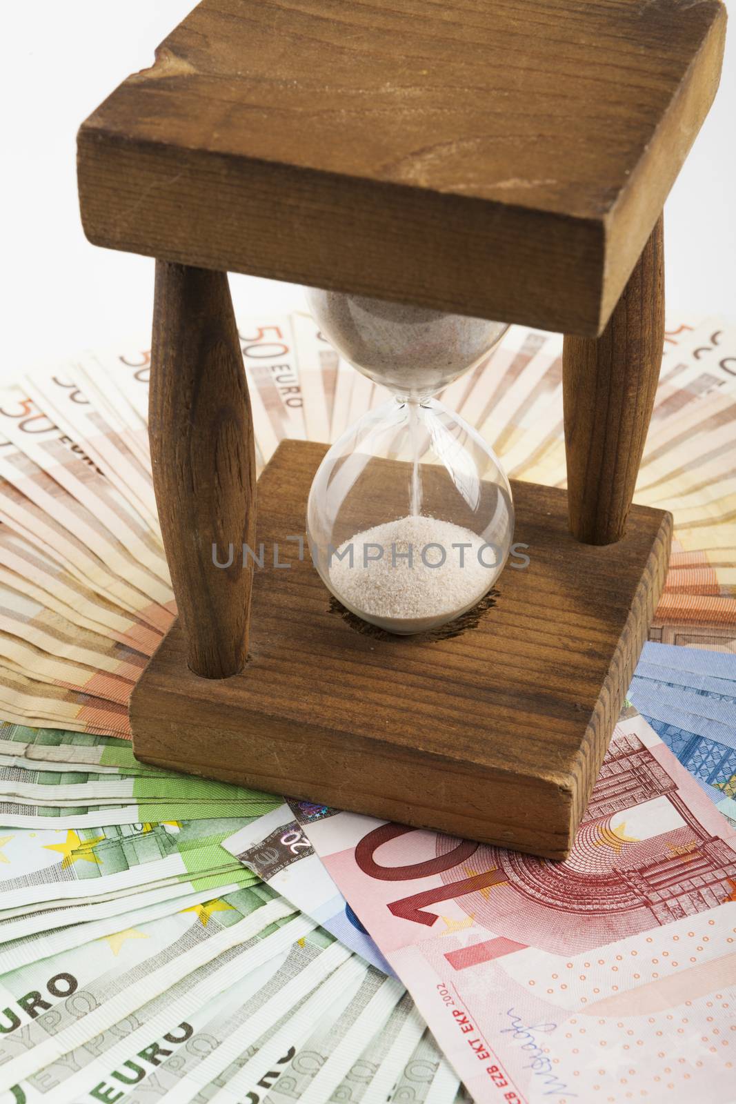 Wood hourglass closeup in a middle of euro banknotes circle