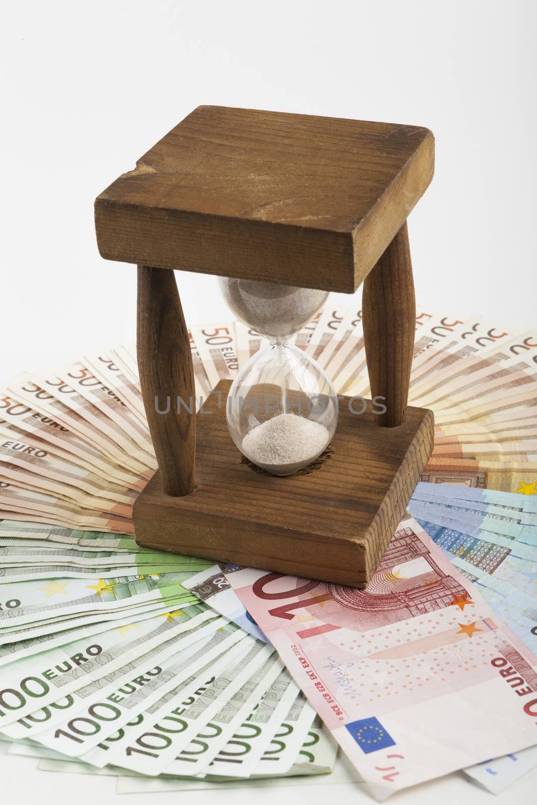 Old wooden Hourglass in the middle on euro banknotes circle