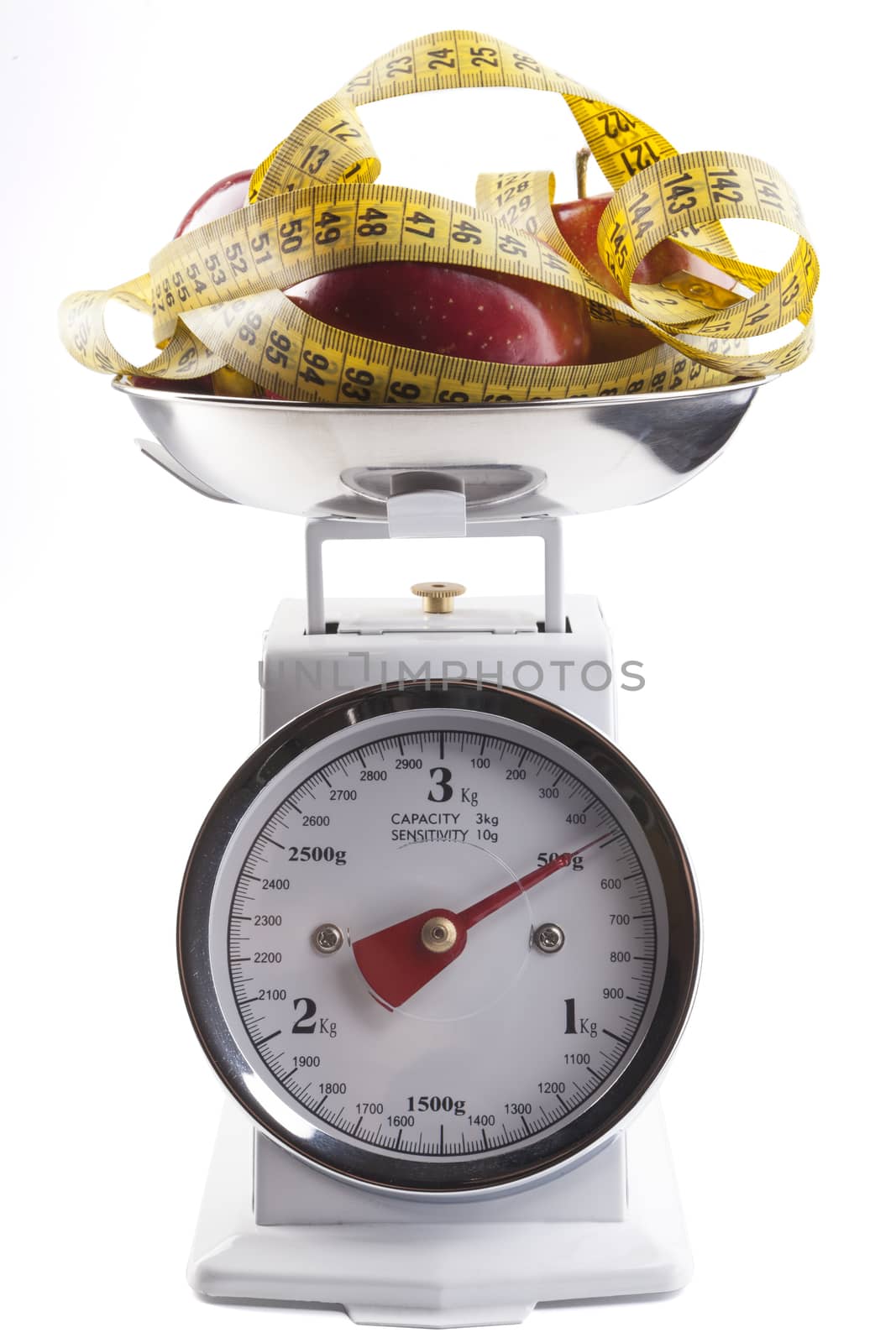 Red apple with  yellow measuring tape on kitchen scale isolated on white