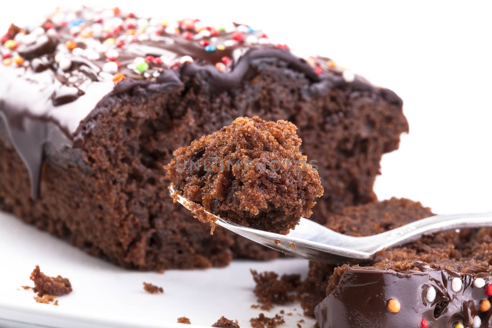 Sweet chocolate cake with colored candy on the top close-up isolated on white