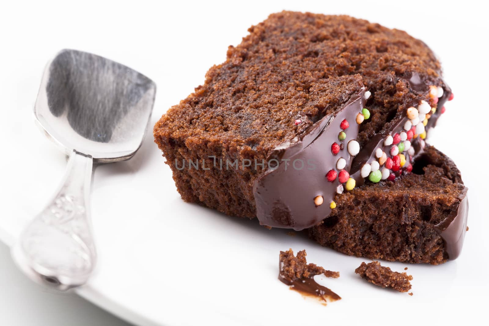 Sweet chocolate cake slice with colored candy on the top  isolated on white