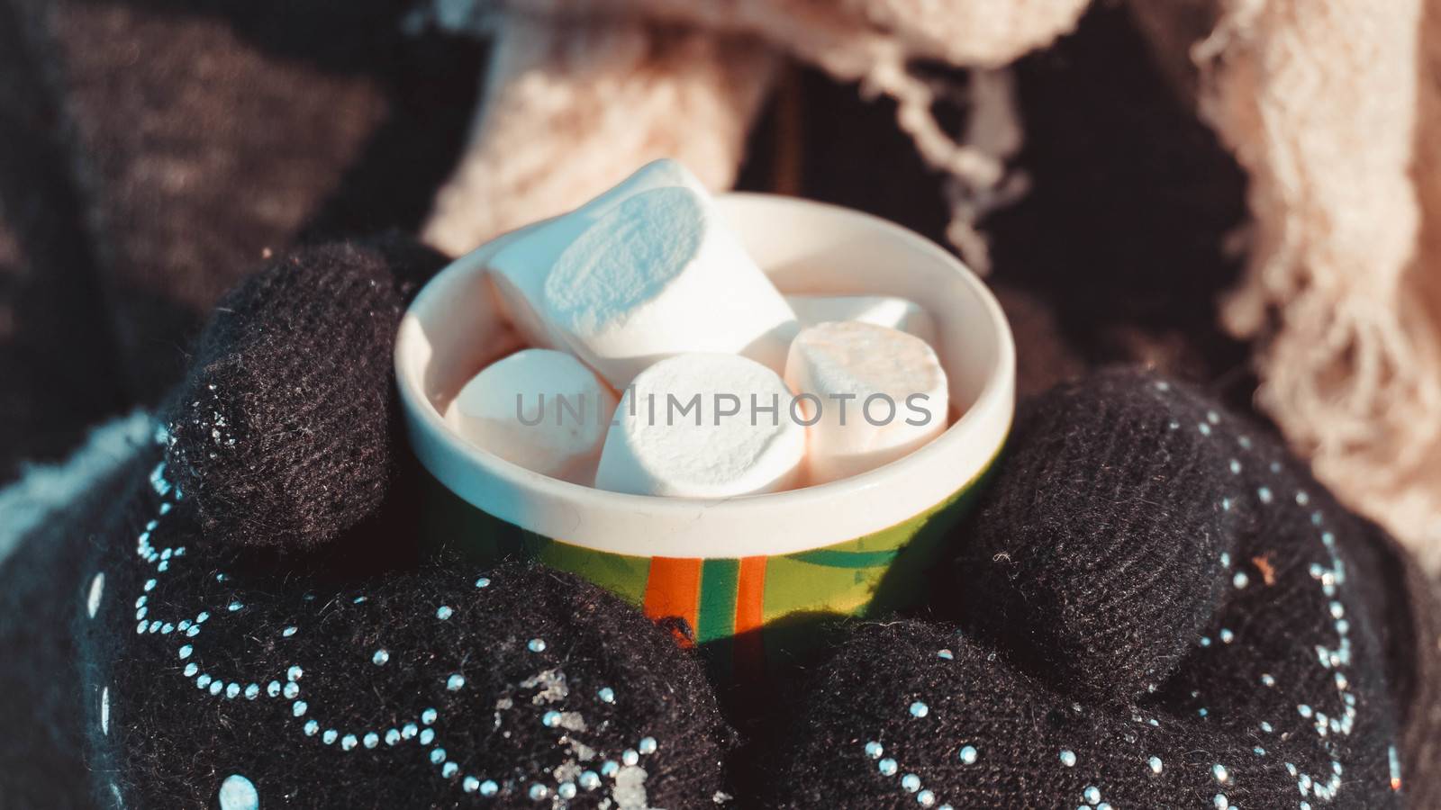 A cup of cocoa with marshmallows in hands in mittens. Warm winter background by natali_brill
