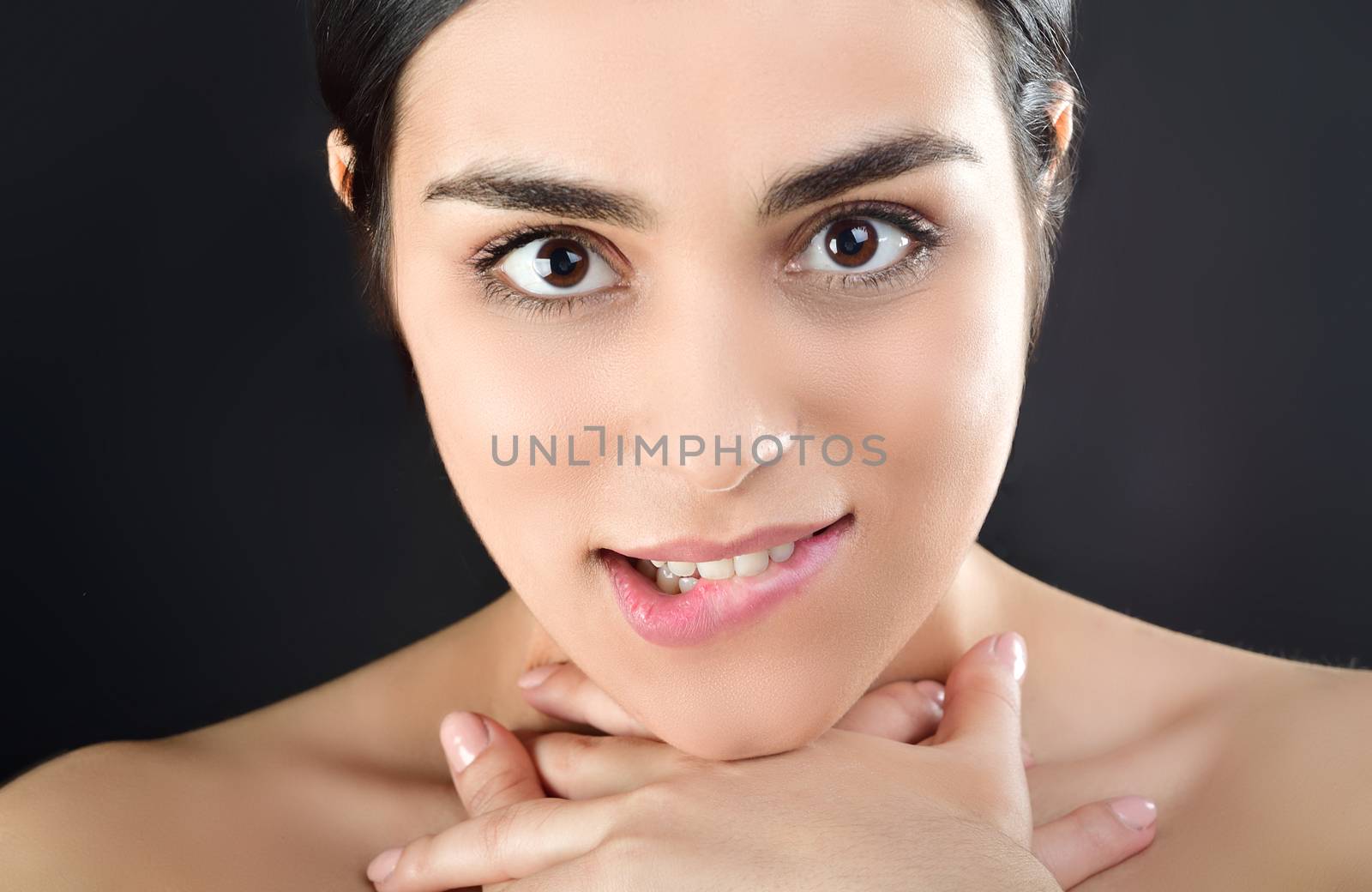 A young sexy woman passionately looks at the camera, pressing her throat with her hands