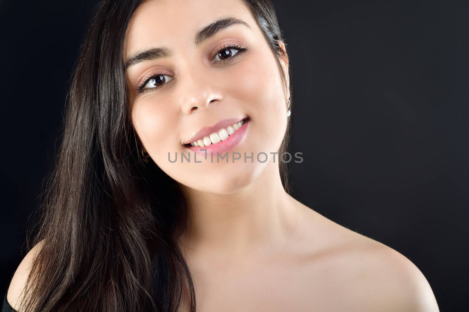 Portrait of a beautiful girl on a black background which is naked on the shoulders