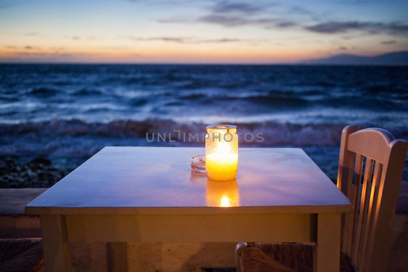 romantic table with burning candle by the sea at night