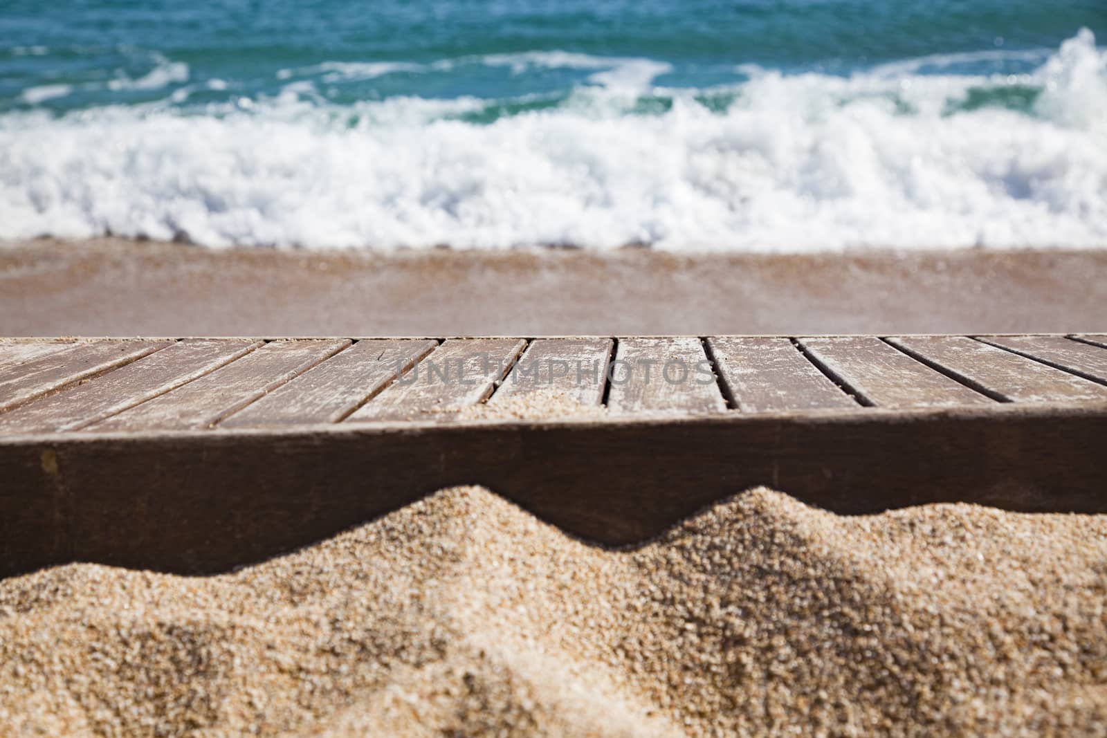 wooden plank in sand and blue sea in the background