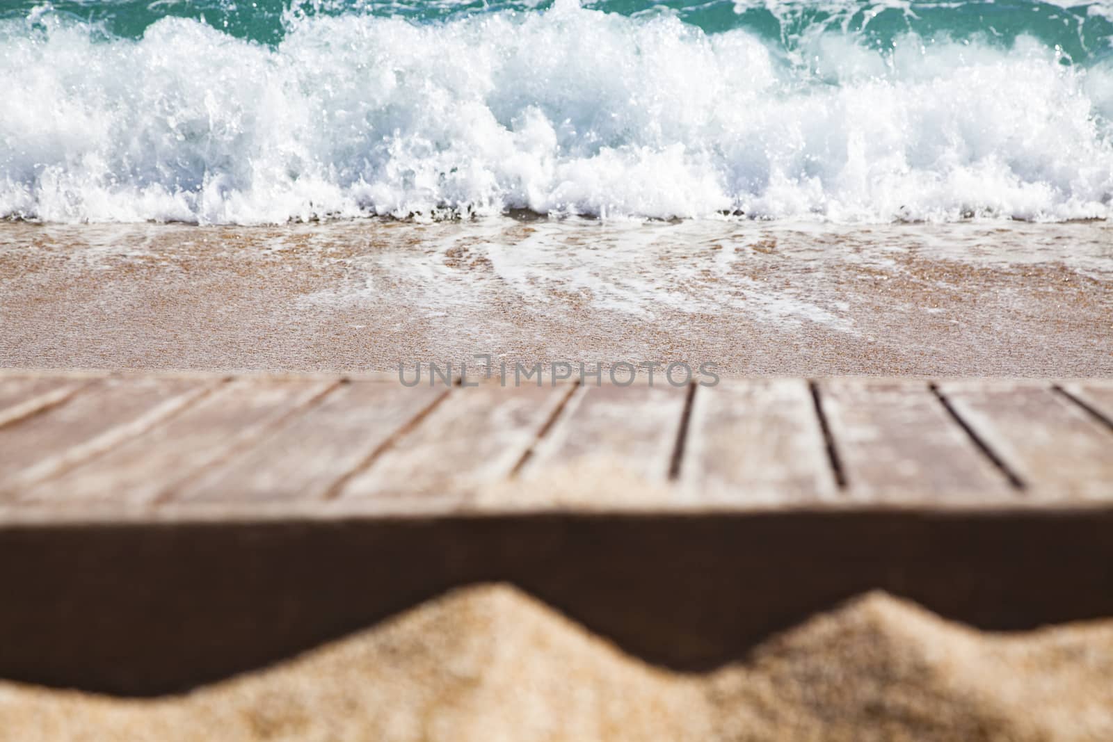 wooden plank in sand and blue sea in the background