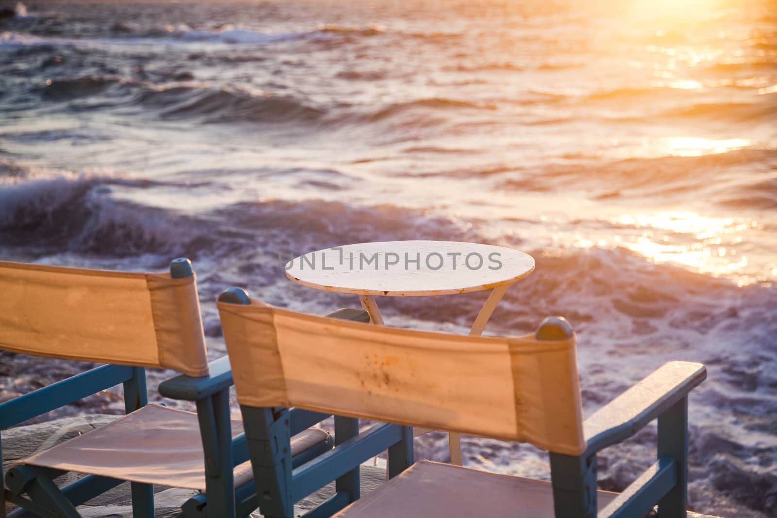 table and chairs near the waves at sunset - beach holiday by melis