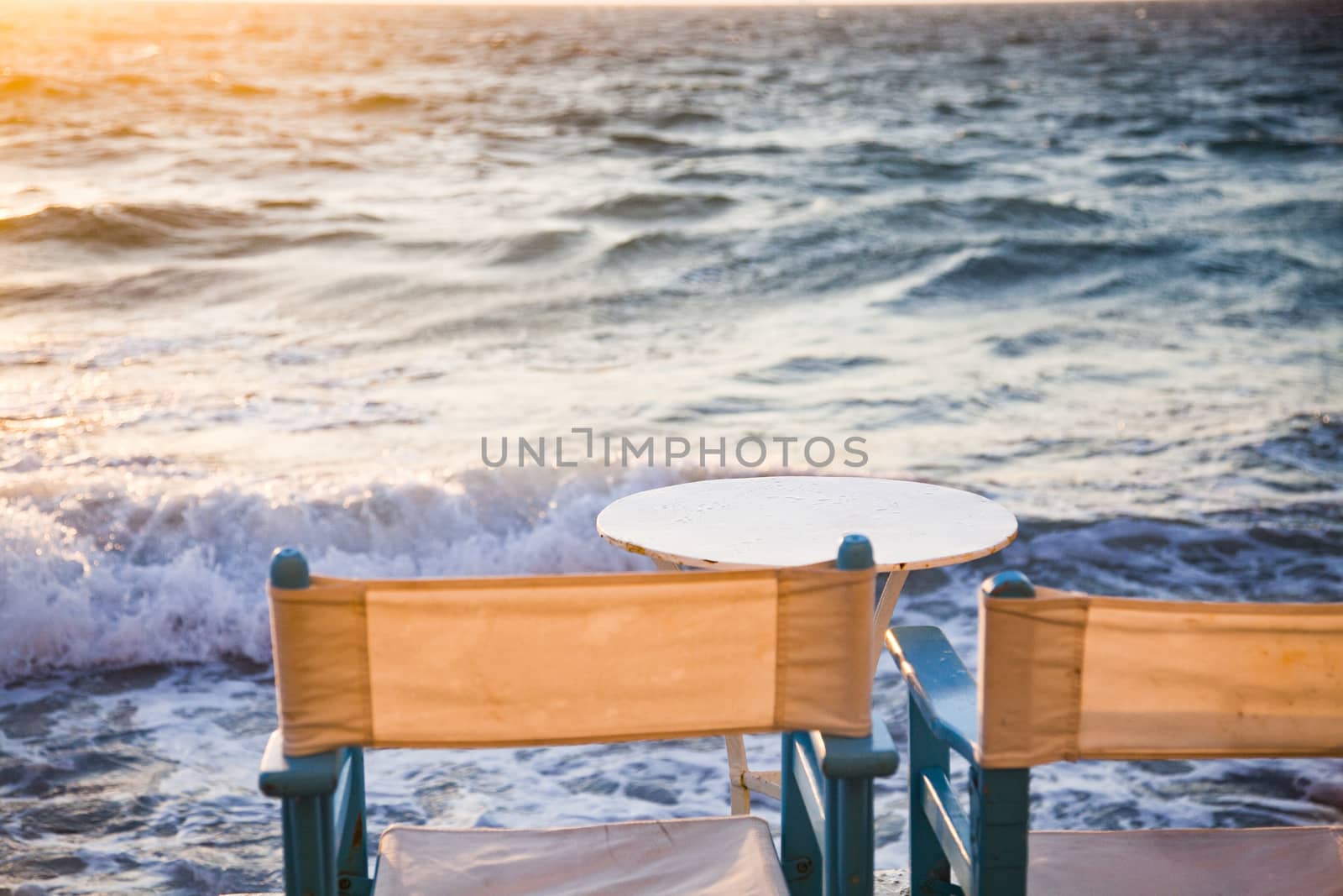 table and chairs near the waves at sunset - beach holiday