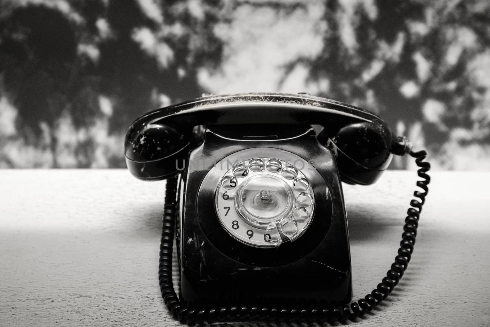 Vintage telephone on old table black and white photo by Anelik