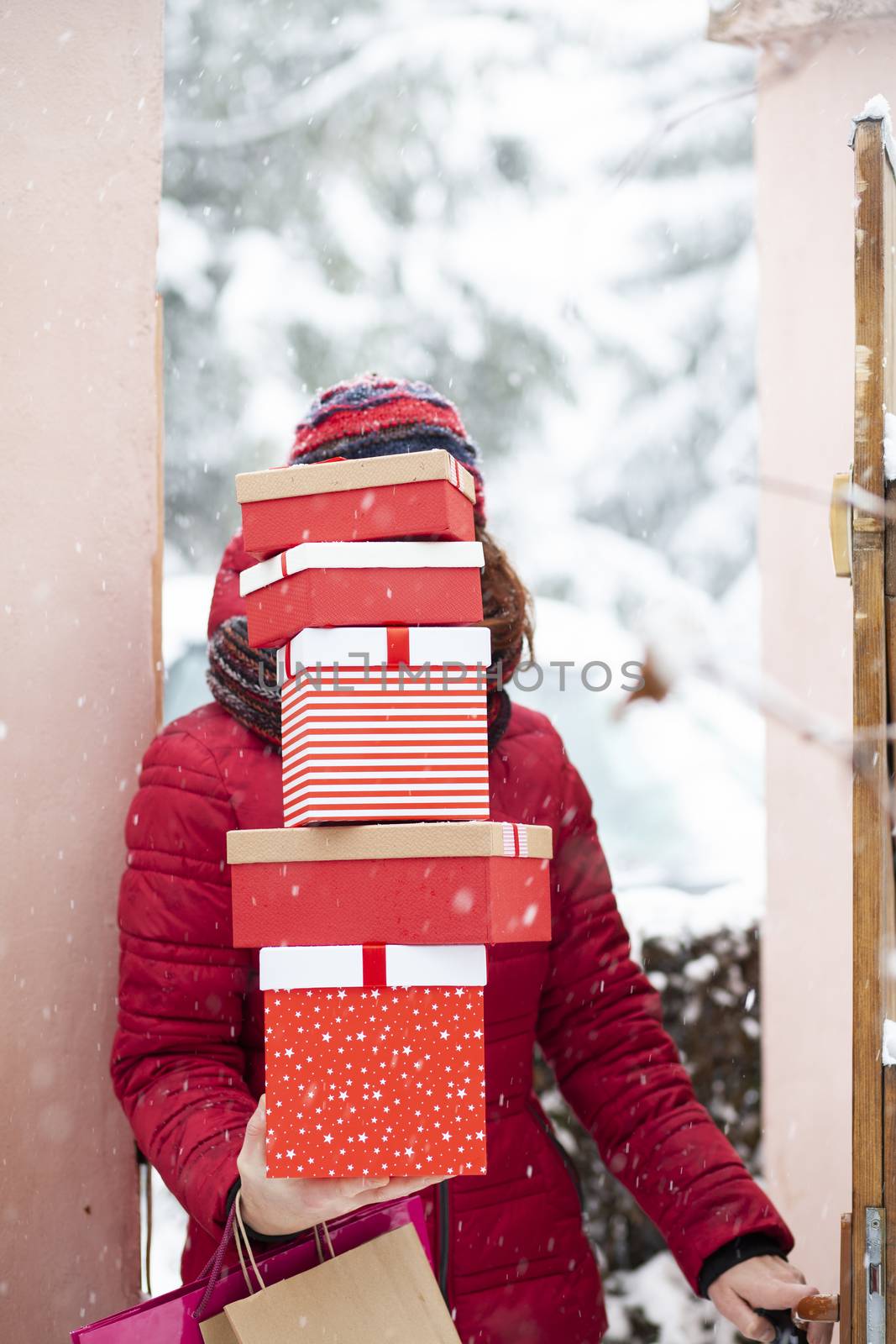 woman returning home from shopping holding pile of christmas present boxes 