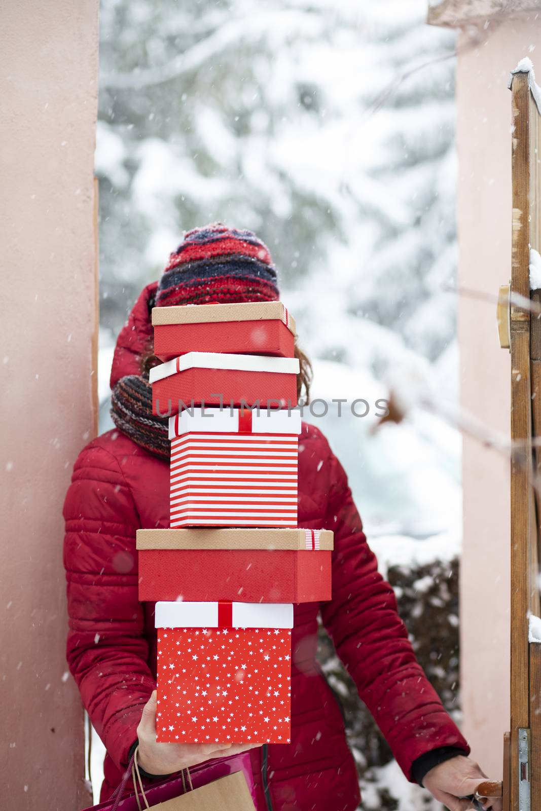 woman returning home from shopping holding pile of christmas present boxes 