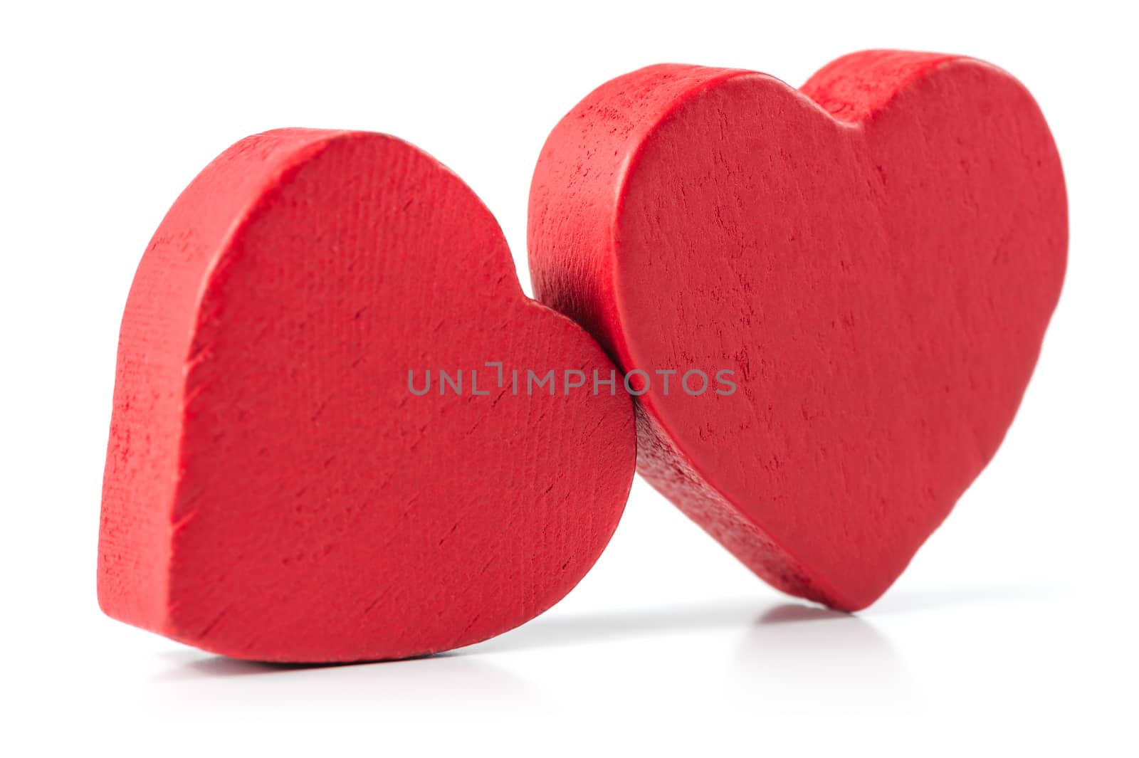 Two red wooden roughly carved hearts isolated on white