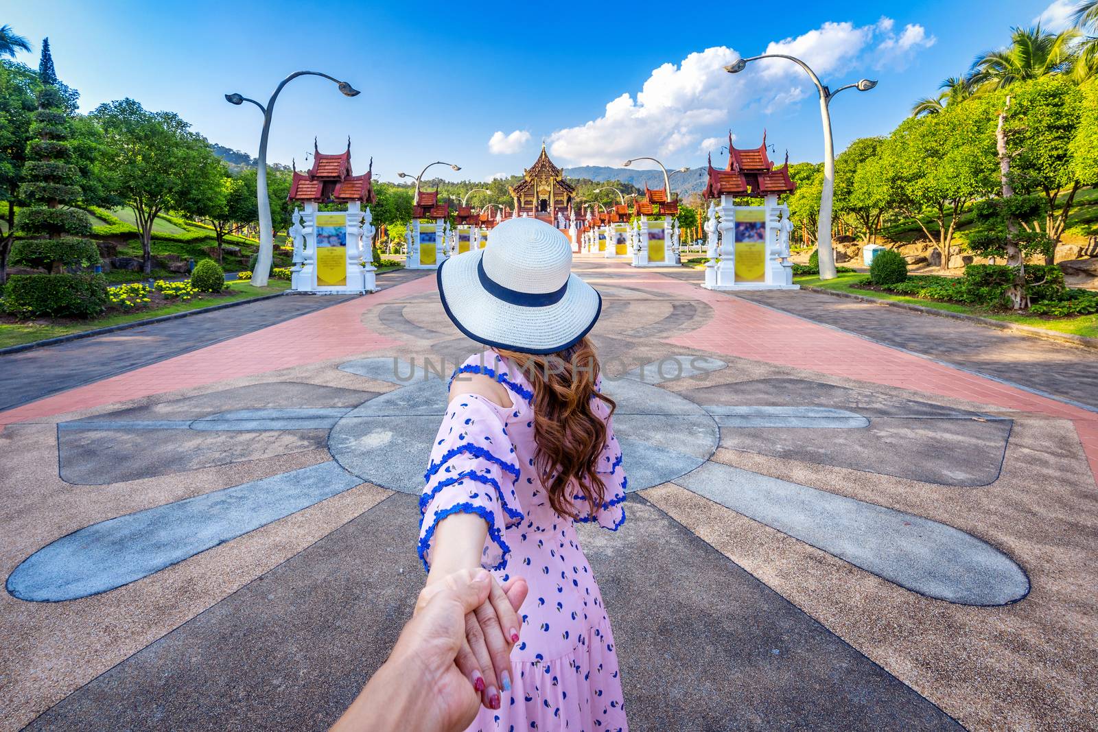 Women tourists holding man's hand and leading him to Ho kham luang northern thai style in Royal Flora ratchaphruek in Chiang Mai,Thailand.