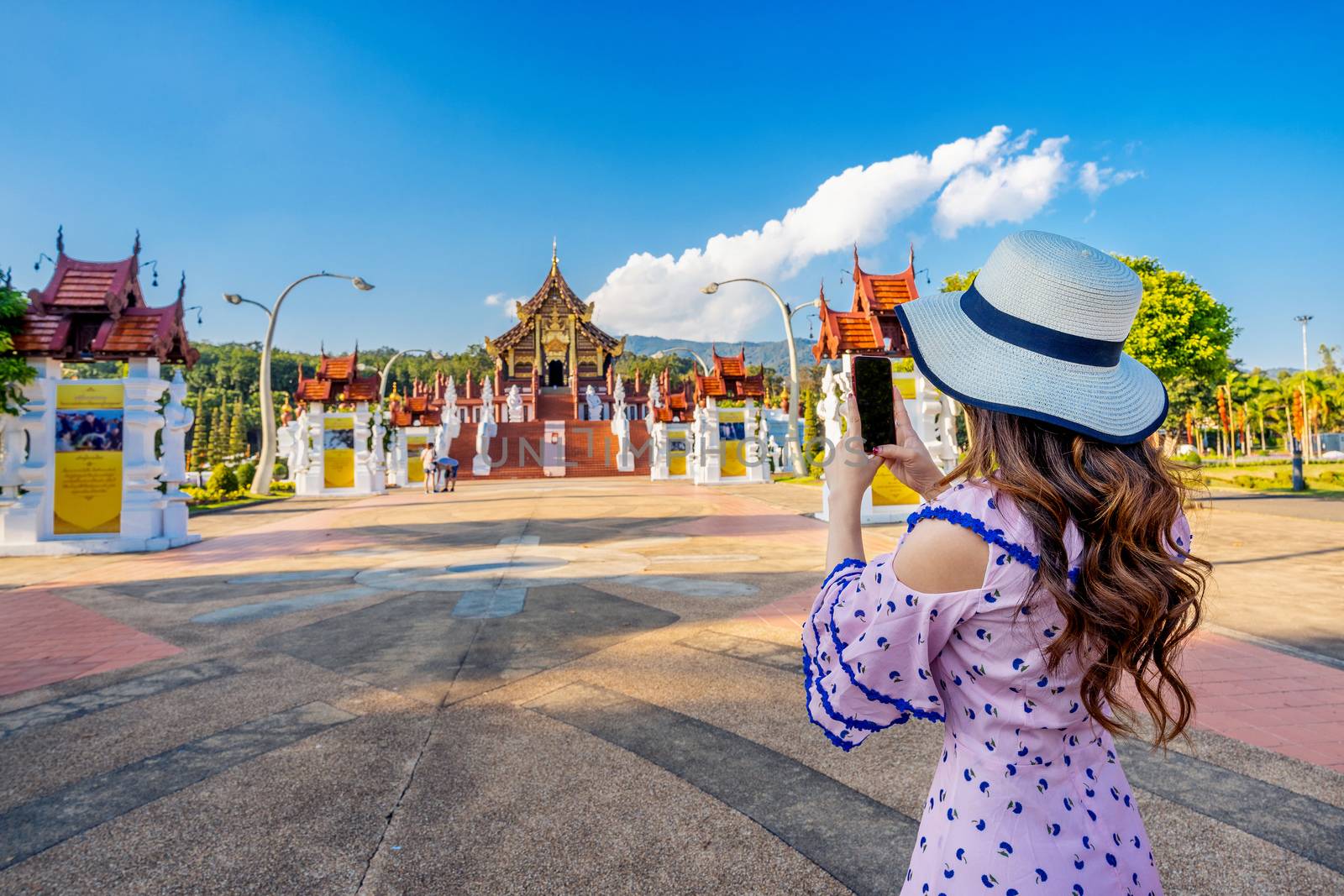 Woman use mobile phone take a photo at Ho kham luang northern thai style in Royal Flora ratchaphruek in Chiang Mai,Thailand. by gutarphotoghaphy