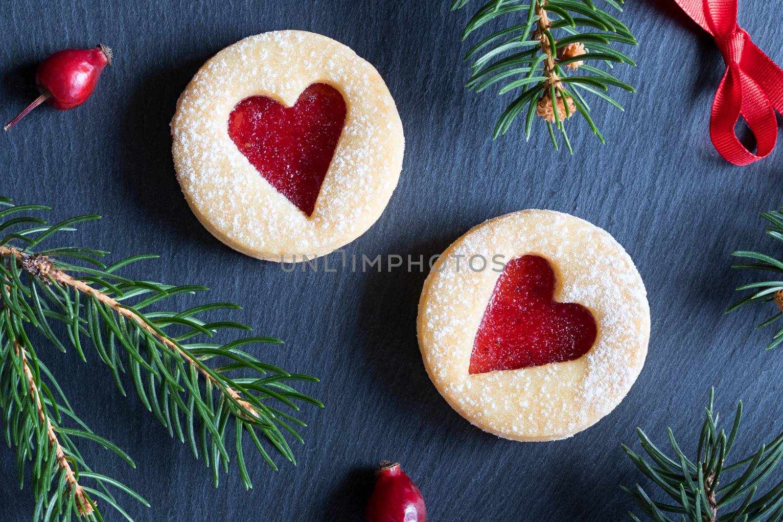 Christmas background with two Linzer Christmas cookies, dried rose hips and spruce branches